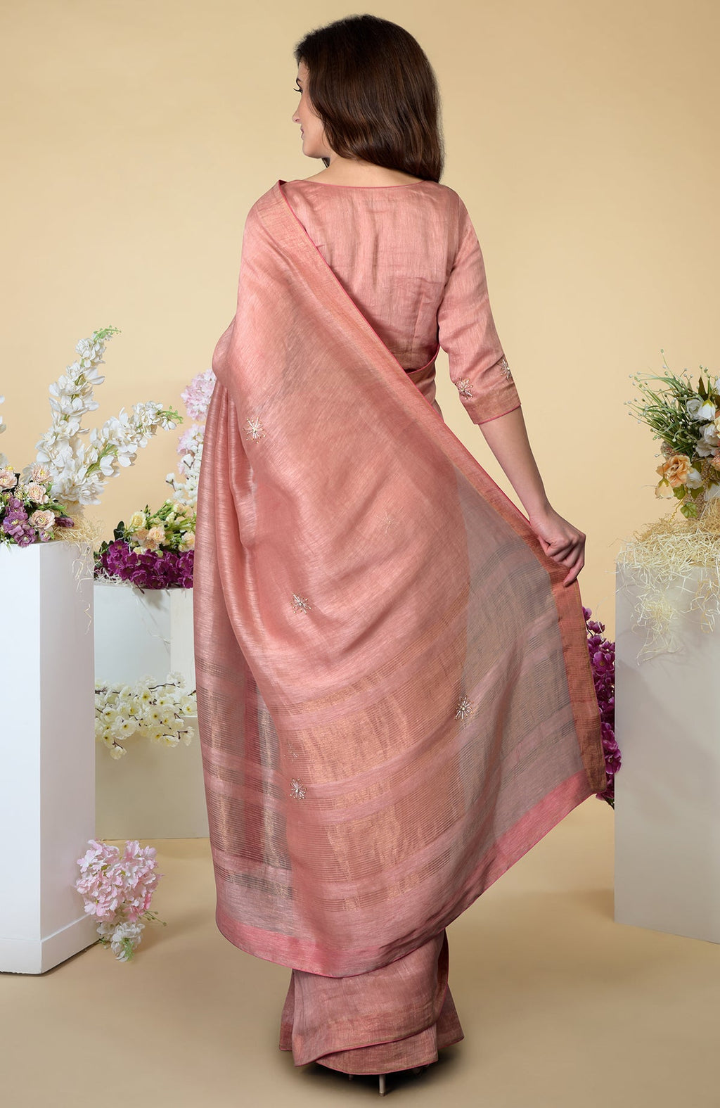 A woman models a pressed rose silk linen saree with zardozi embroidery.