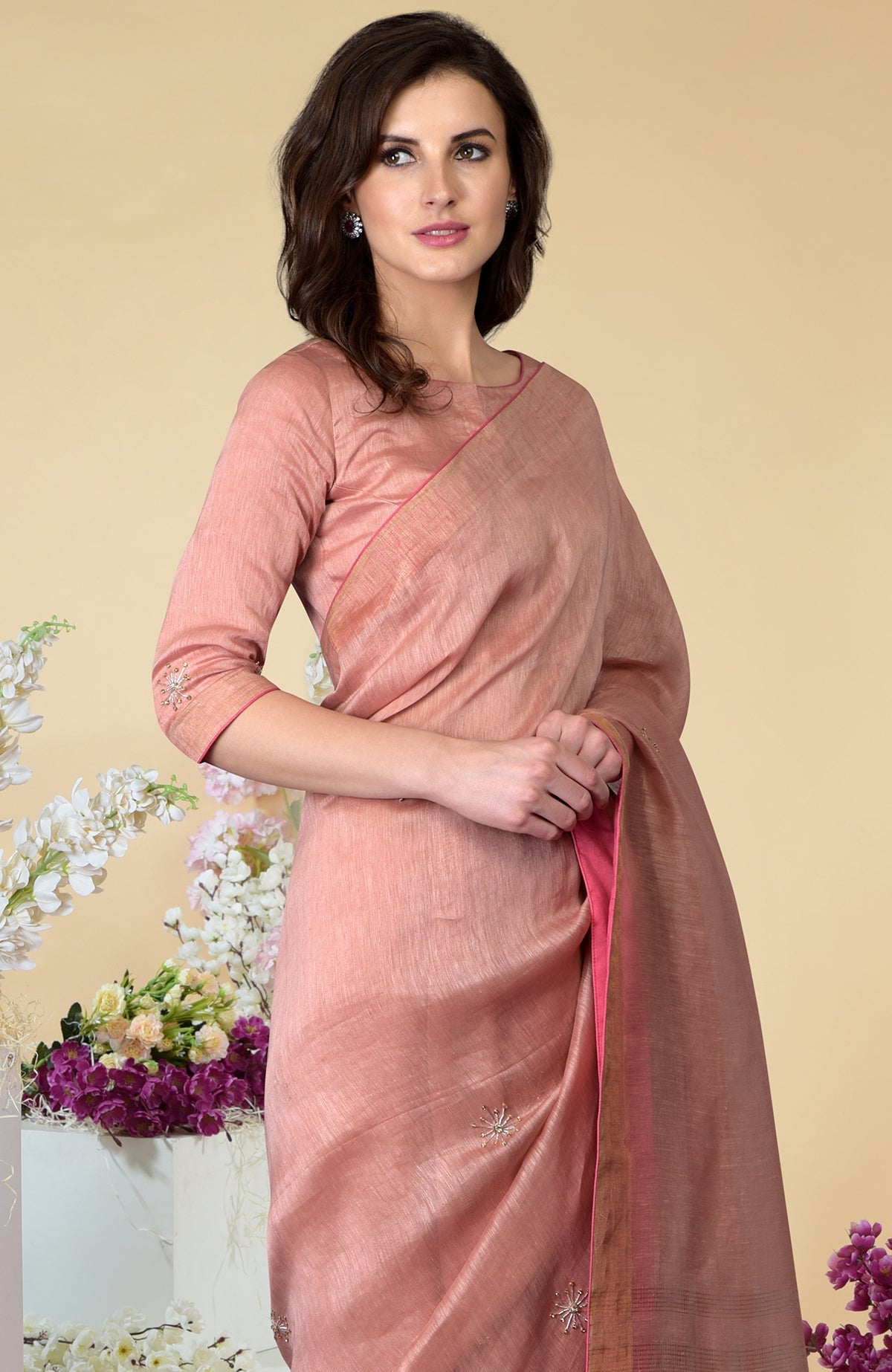 A woman models a pressed rose silk linen saree with zardozi embroidery.