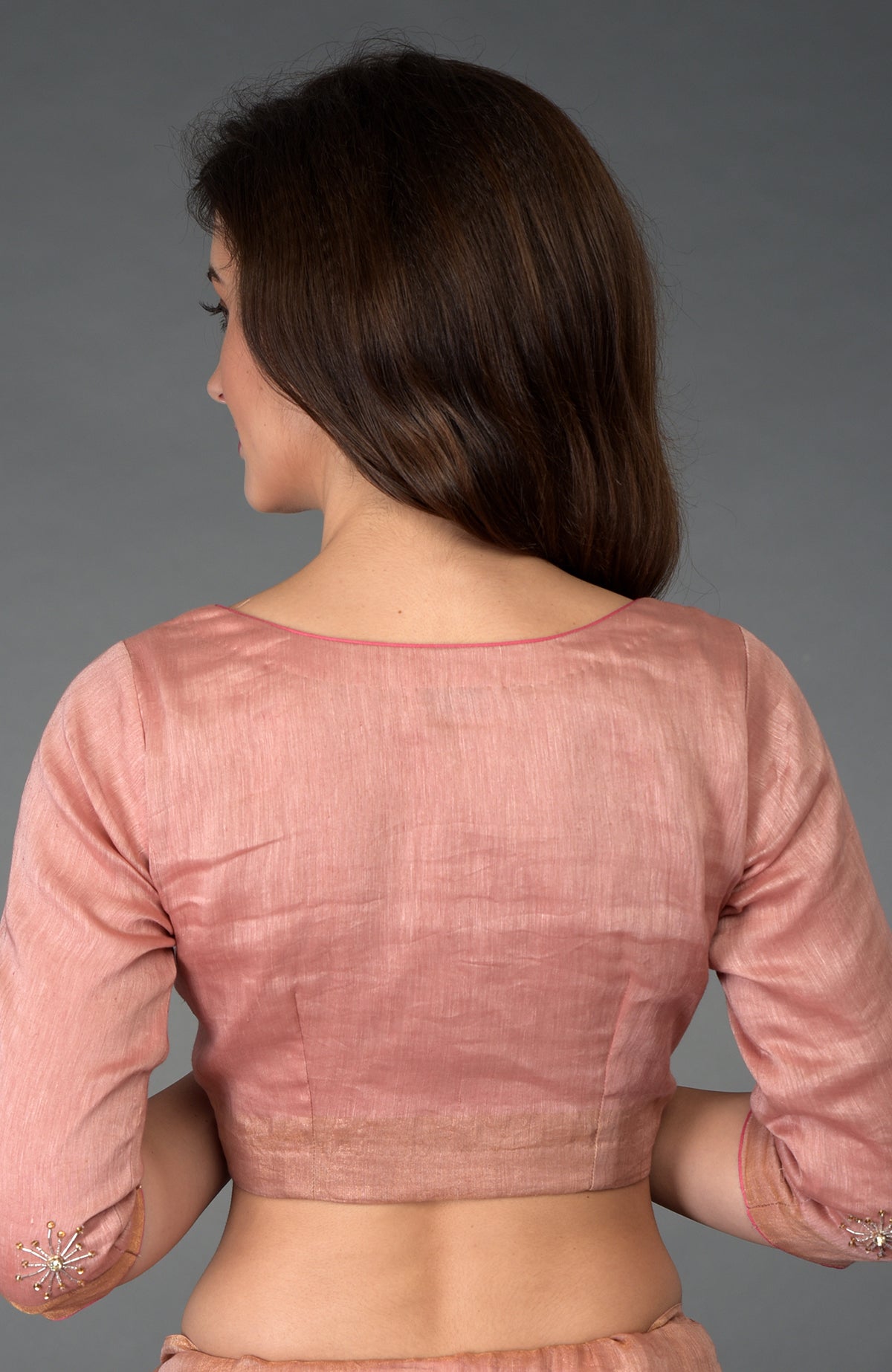 Woman in a pressed rose silk linen blouse with embroidered sleeves.