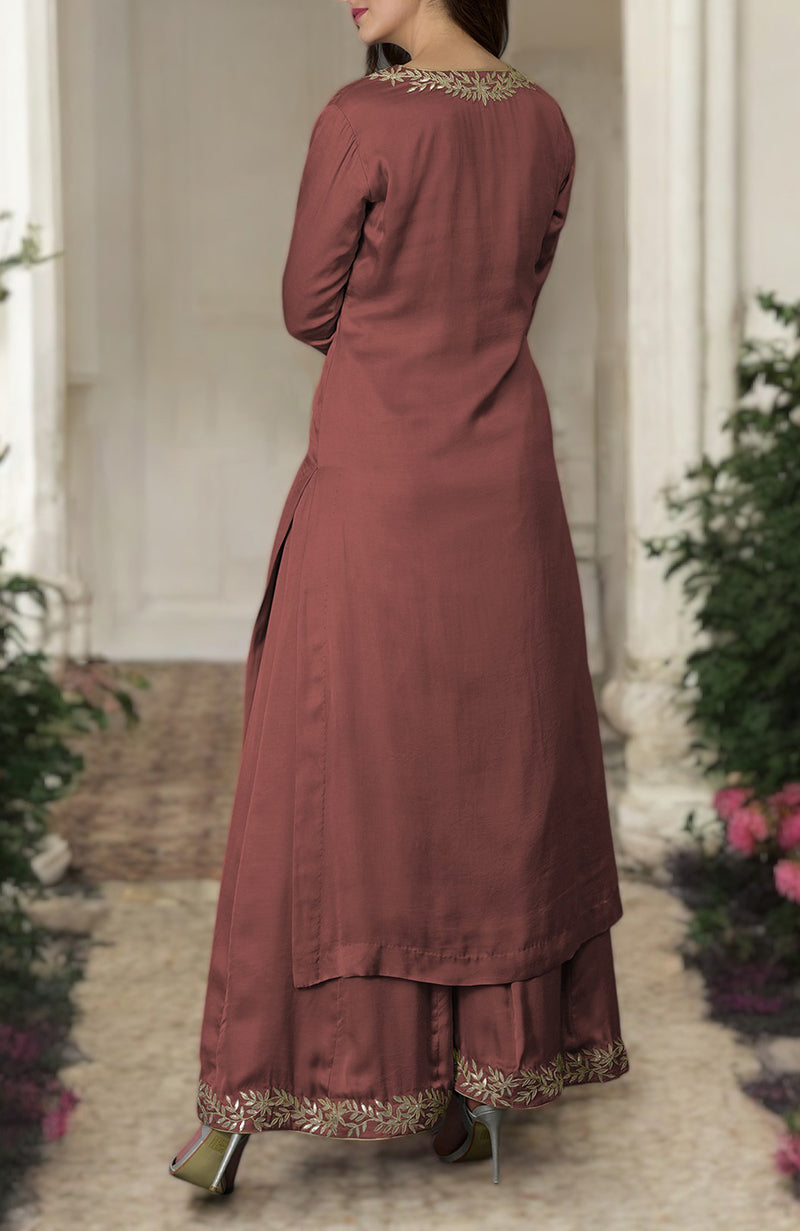 A woman models a chutney-colored kurta and farshi palazzo suit with gold embroidery.