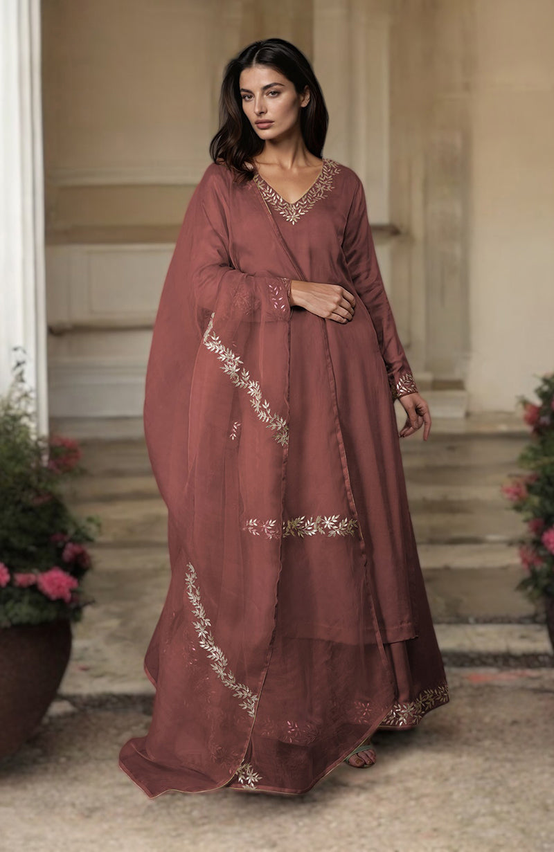 A woman models a chutney-colored farshi palazzo suit with rose gold gota patti embroidery.