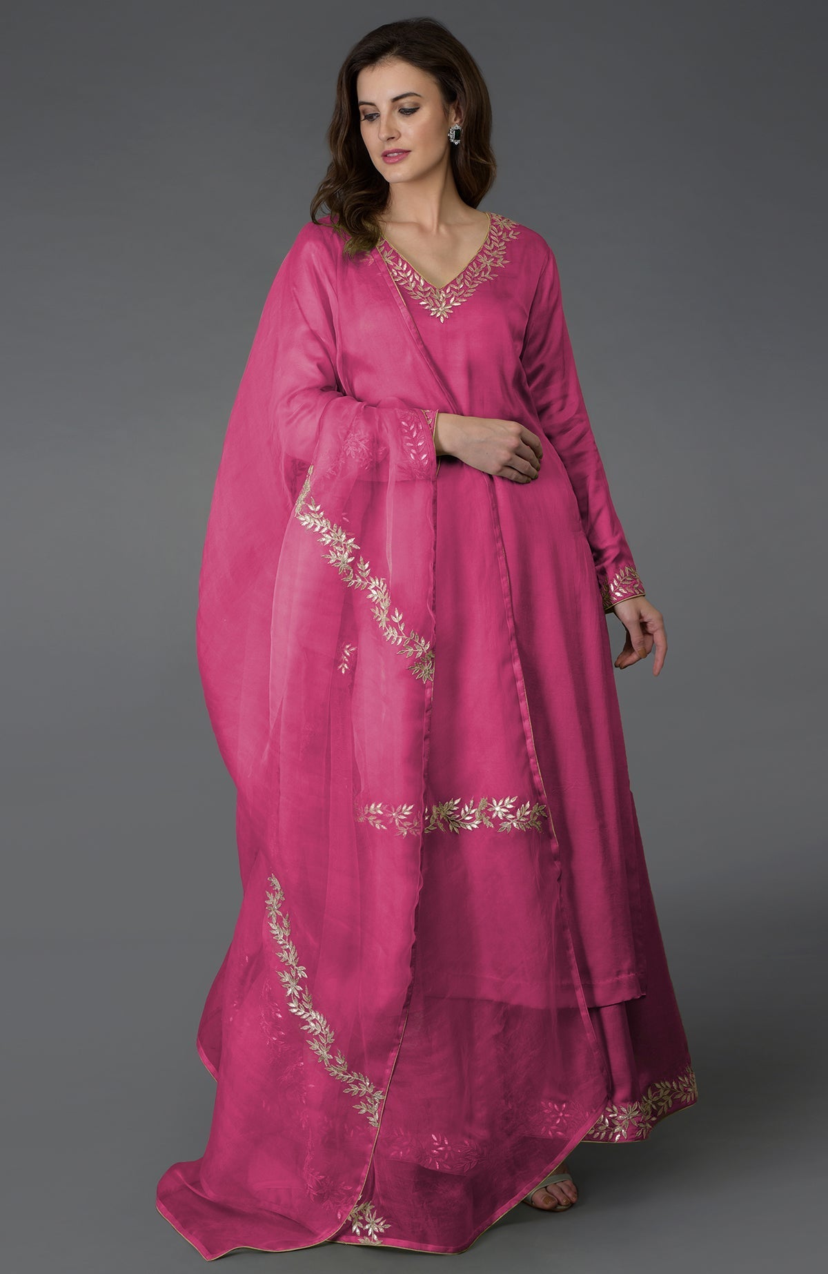 A woman models a chutney pink palazzo suit with gold gota patti embroidery.