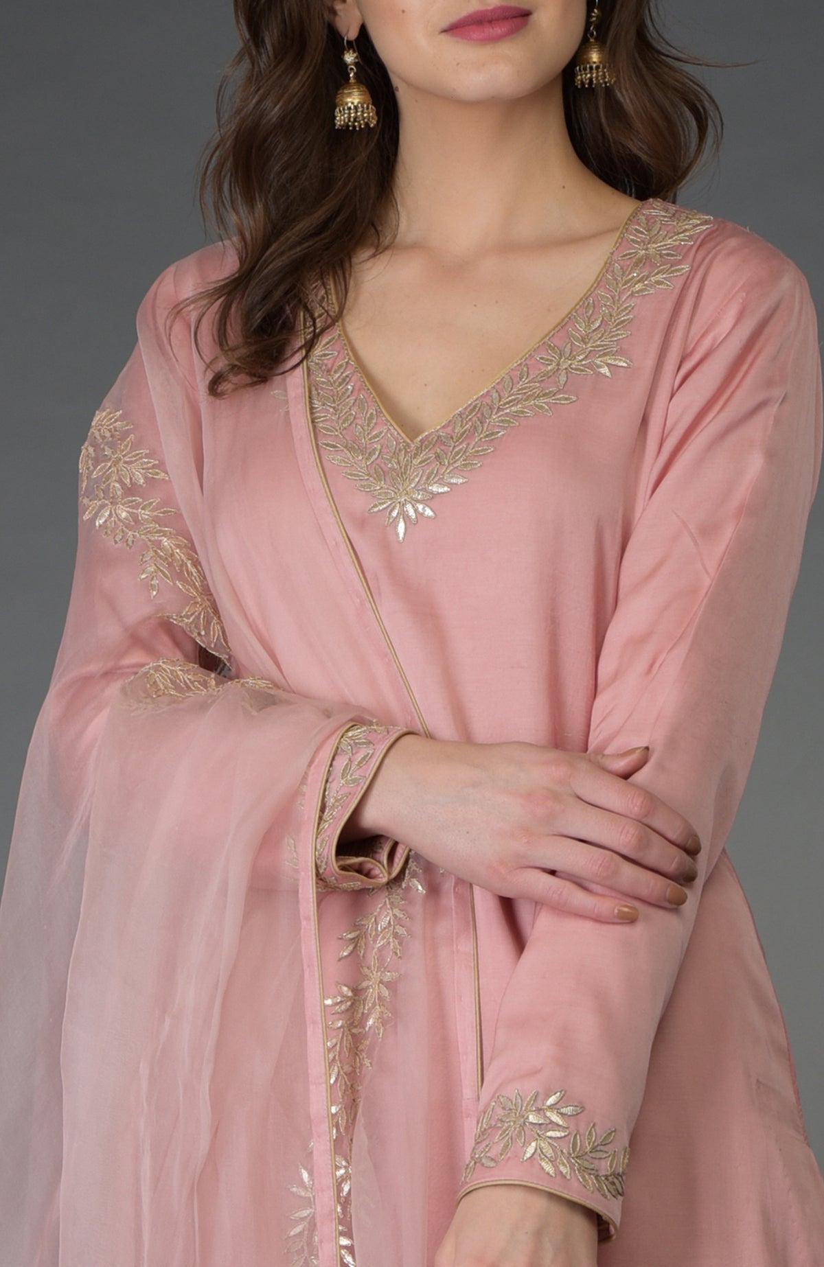 A woman in a pearl pink kurta with gold gota patti embroidery and matching dupatta.