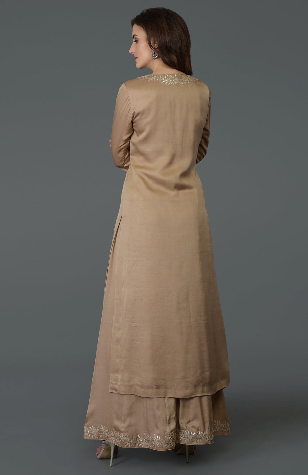 A woman models a beige gota patti work farshi palazzo suit with embroidery.