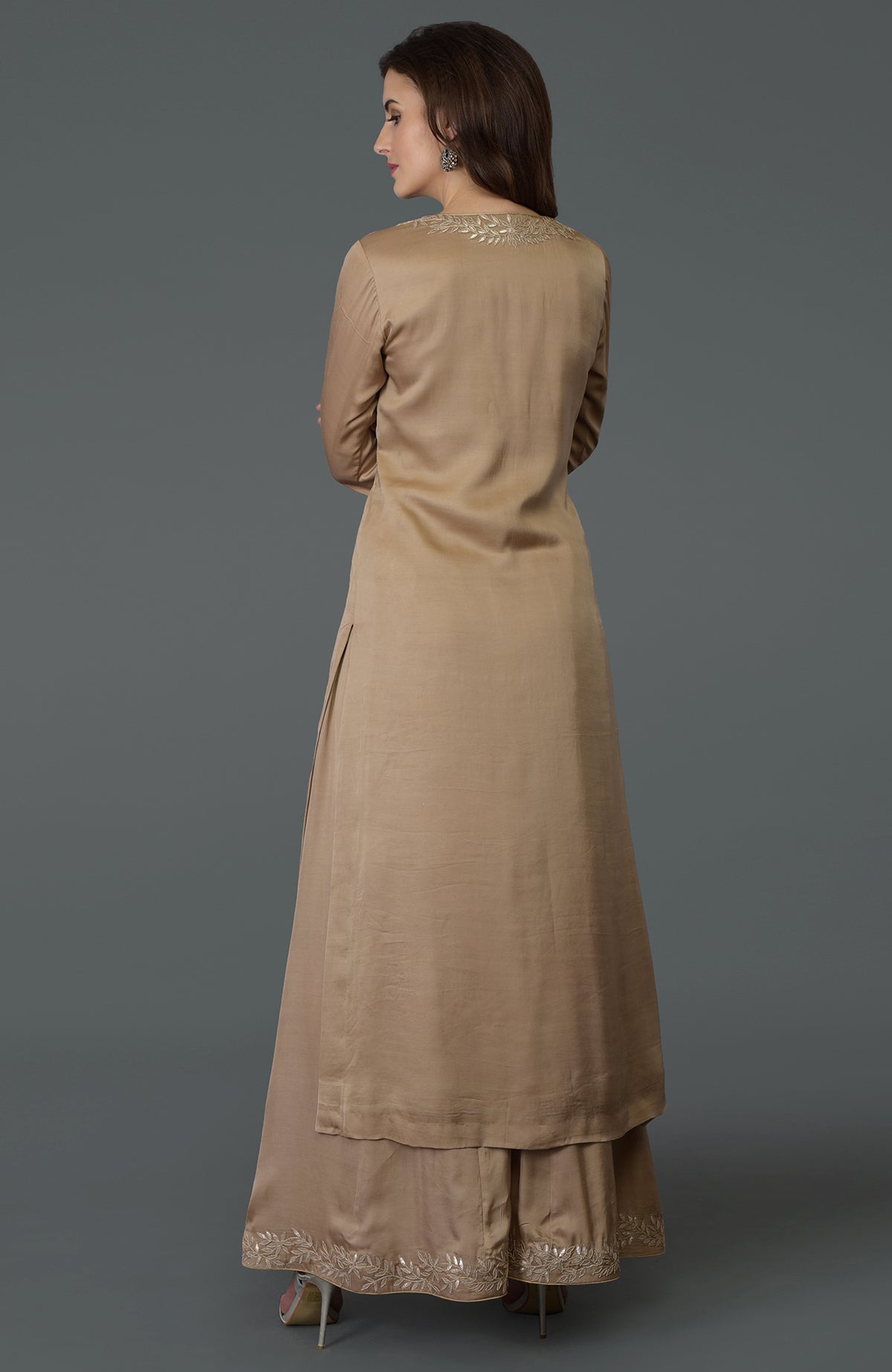 A woman models a beige gota patti work farshi palazzo suit with embroidery.