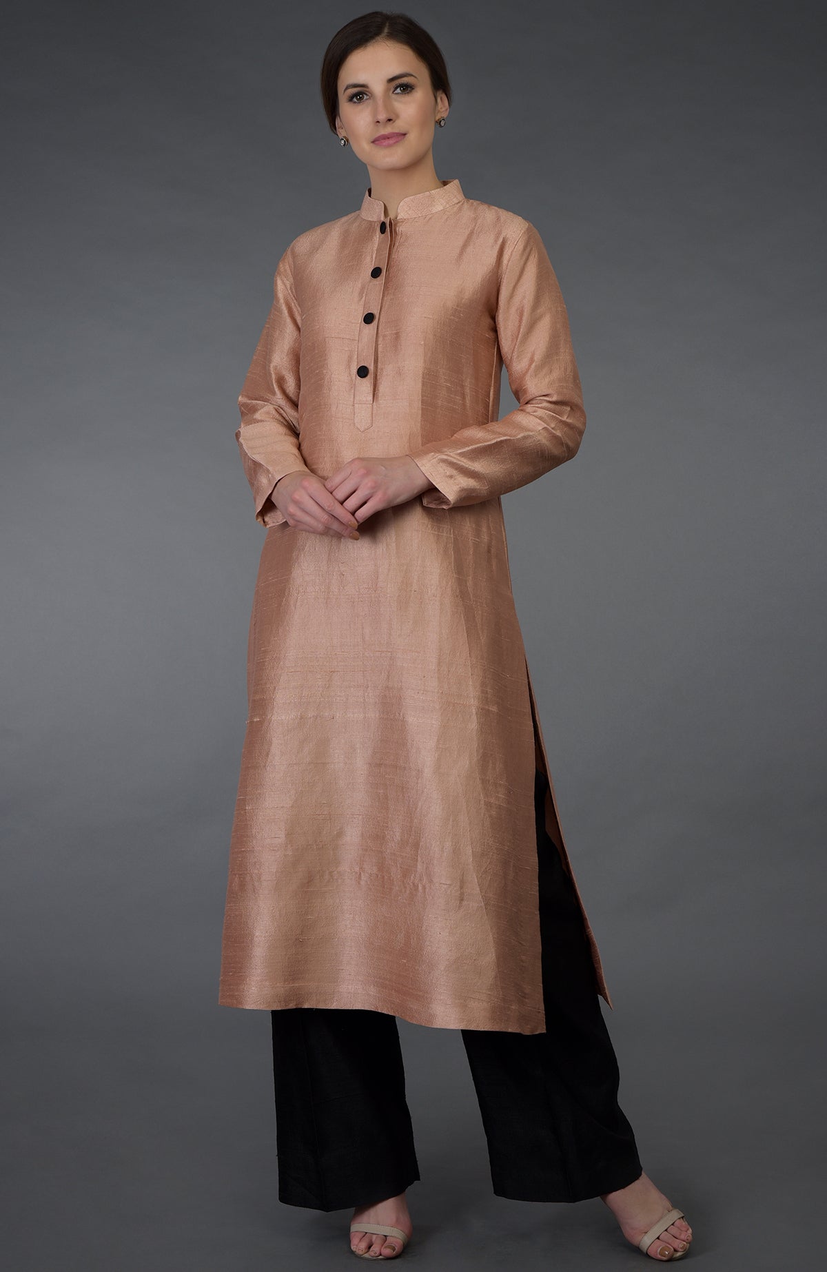 A woman models a pressed rose raw silk kurta with black pants and sandals.