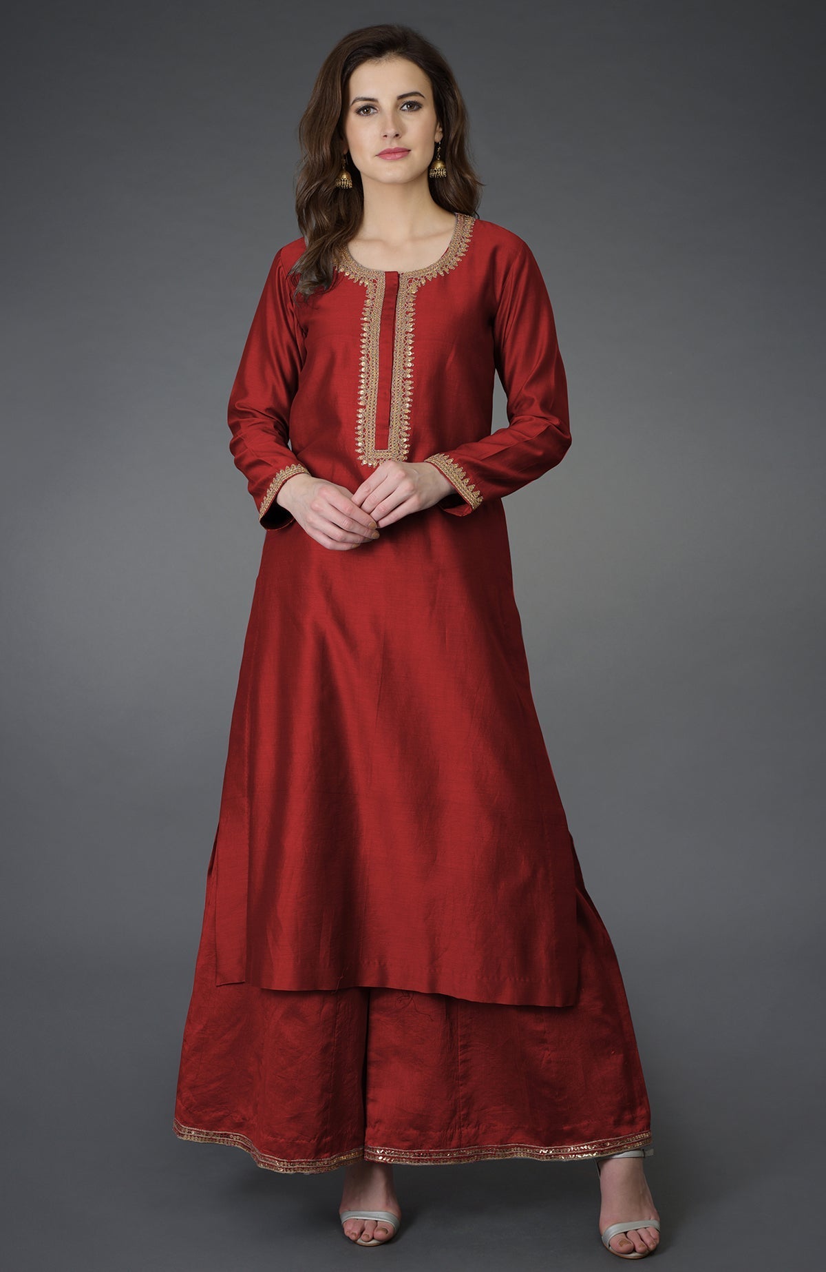 A woman models a red marori and sequin work farshi palazzo suit.