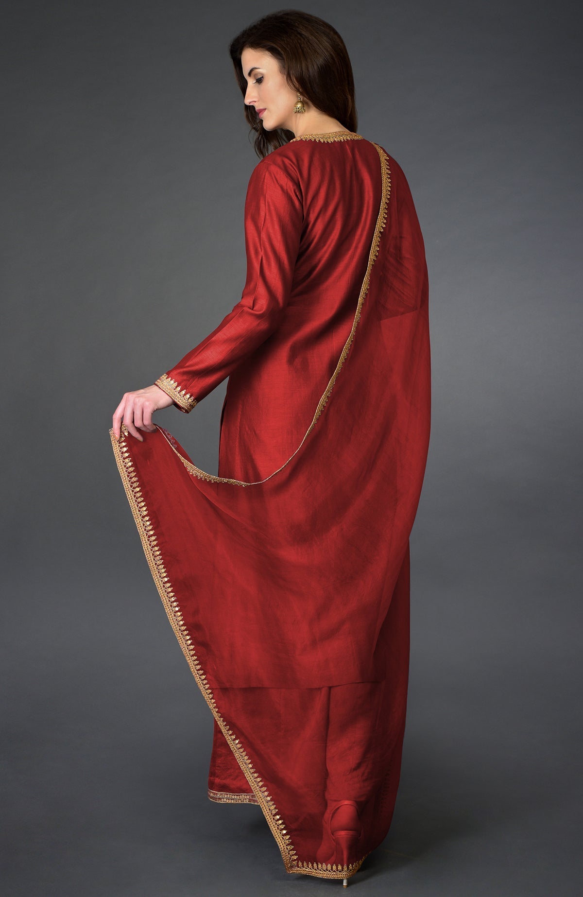 A woman models a red marori and sequin work farshi palazzo suit.