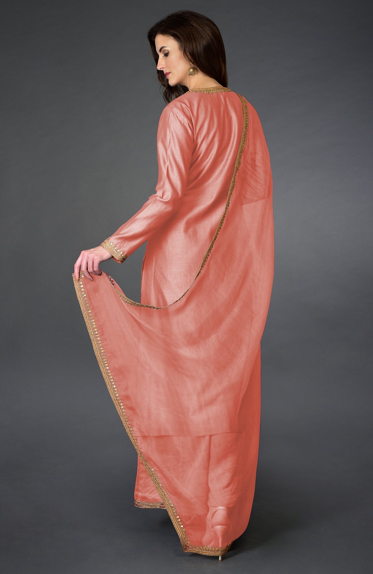 A woman models a terracotta palazzo suit with marori and sequin embroidery.