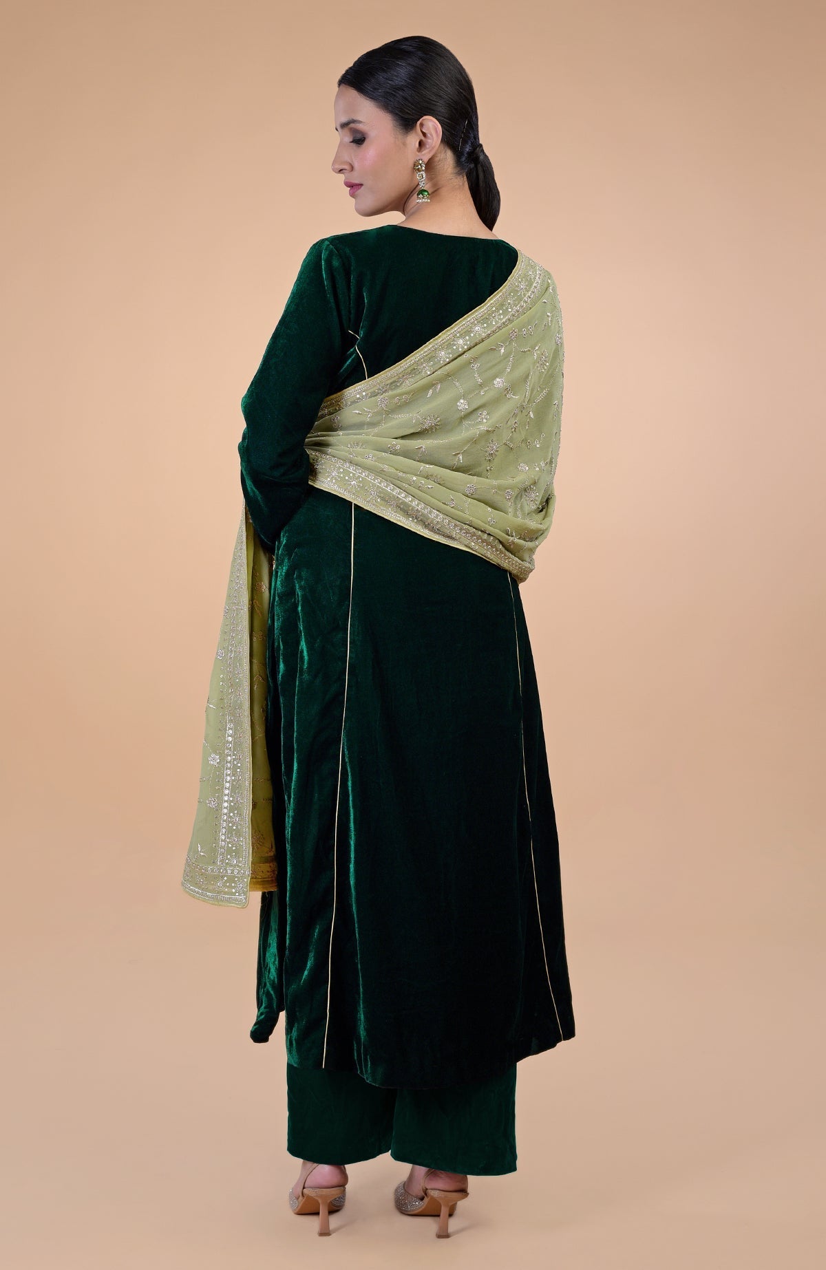 A woman from behind wears a bottle green velvet suit with a bog green embroidered dupatta.