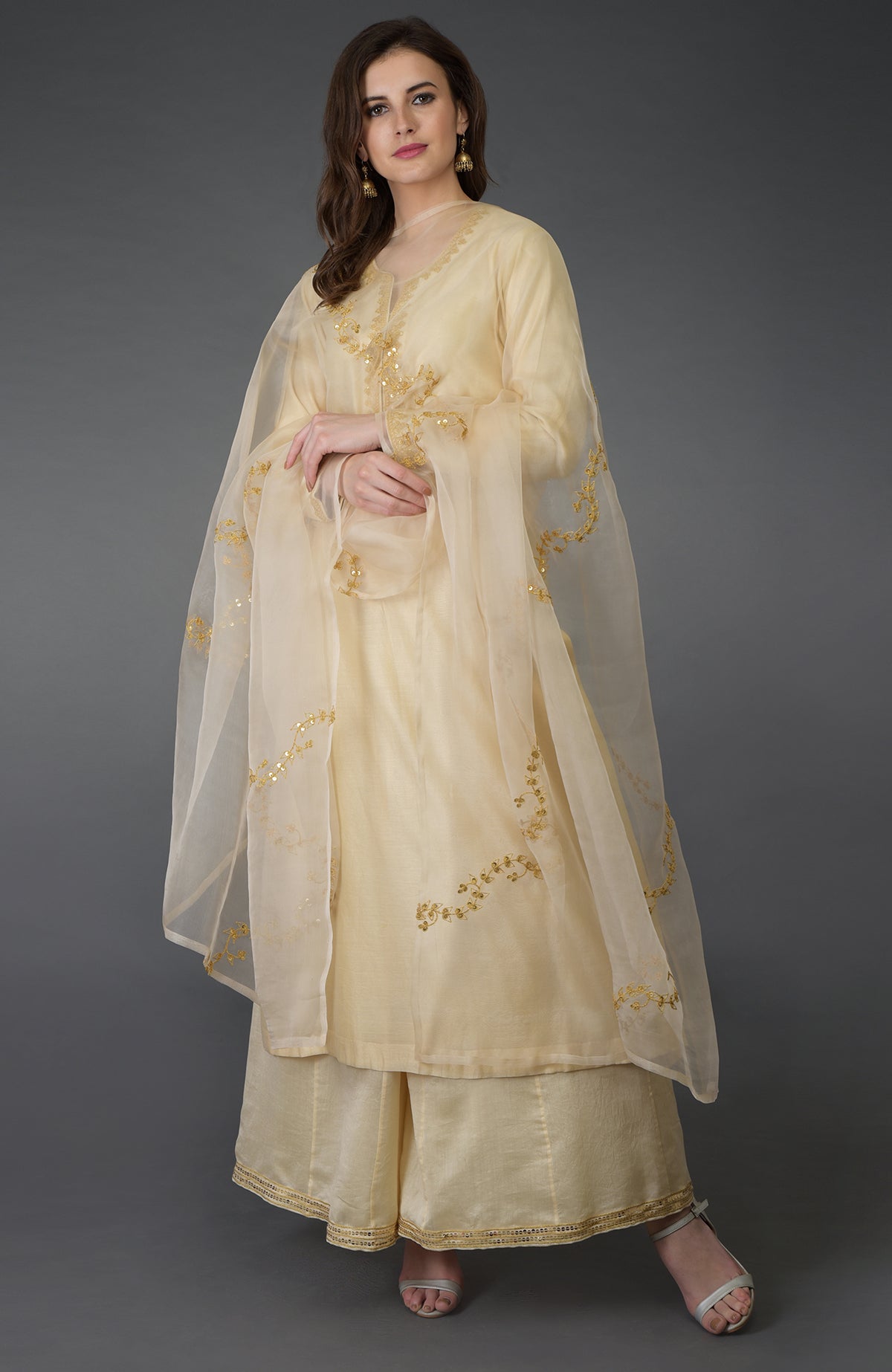 A woman models a cream marori and sequin work farshi palazzo suit.