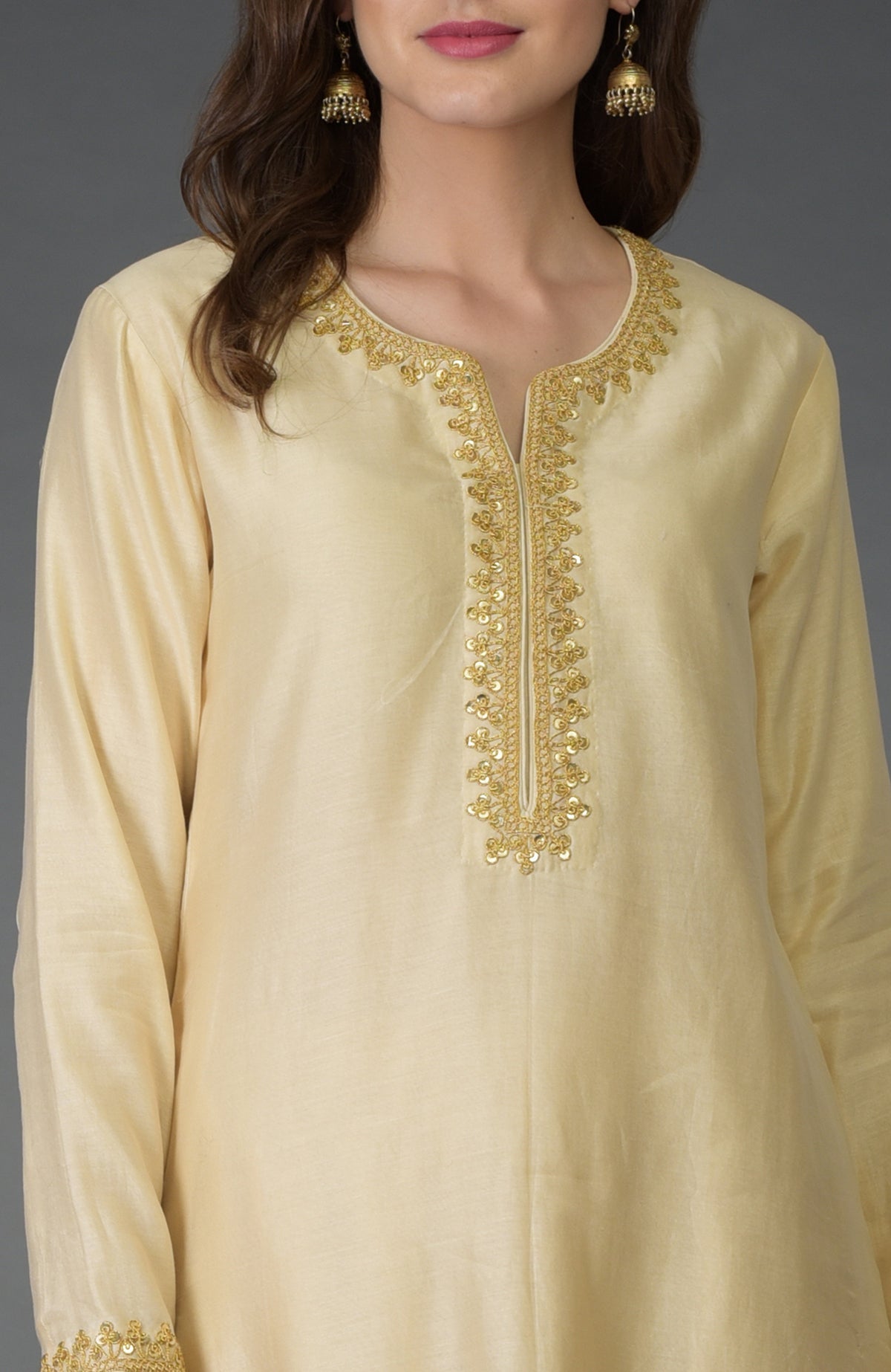 A woman wears a cream kurta with gold marori and sequin embroidery.