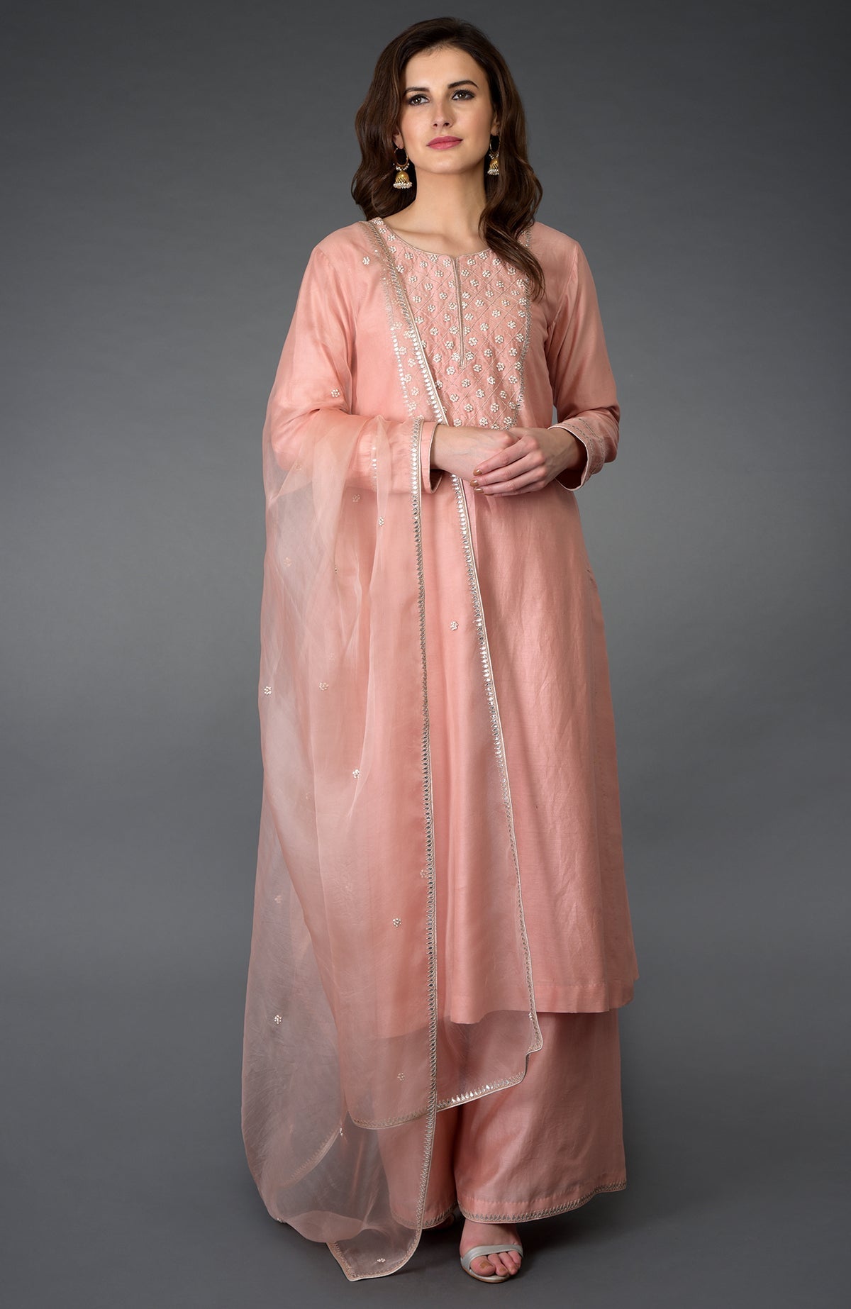 A woman models a pressed rose farshi suit with zardozi, gota patti, and pearl beads.