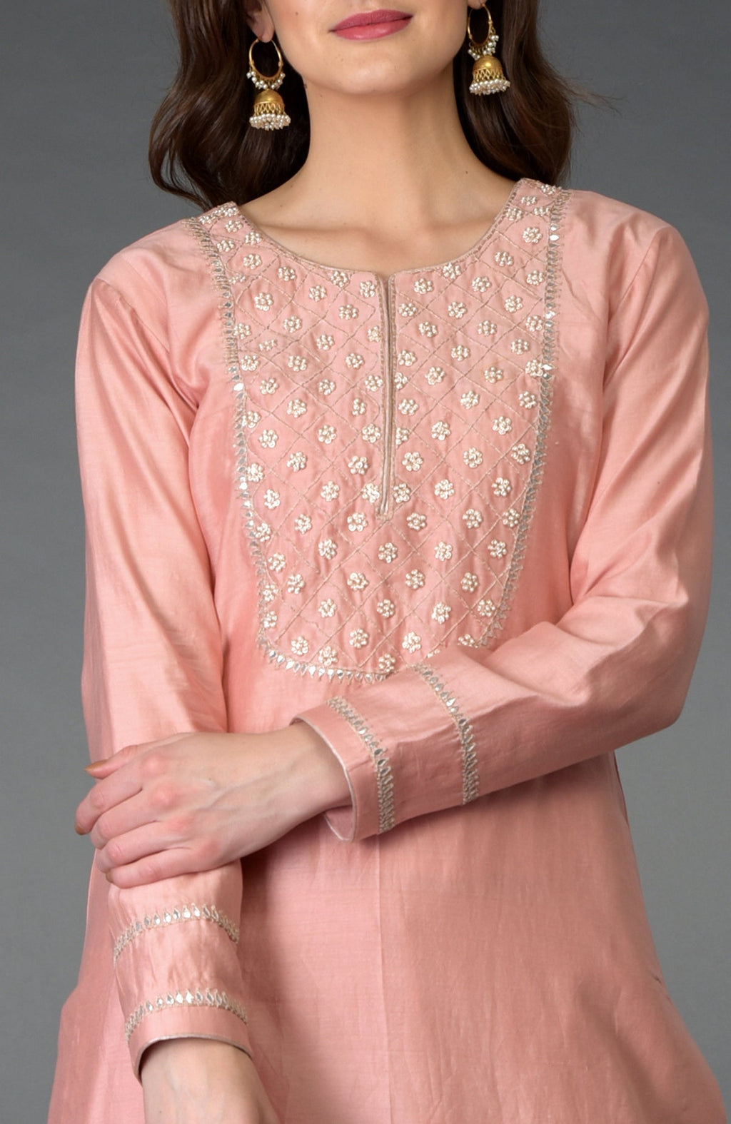 A woman models a pressed rose zardozi gota patti and pearl beads farshi suit.