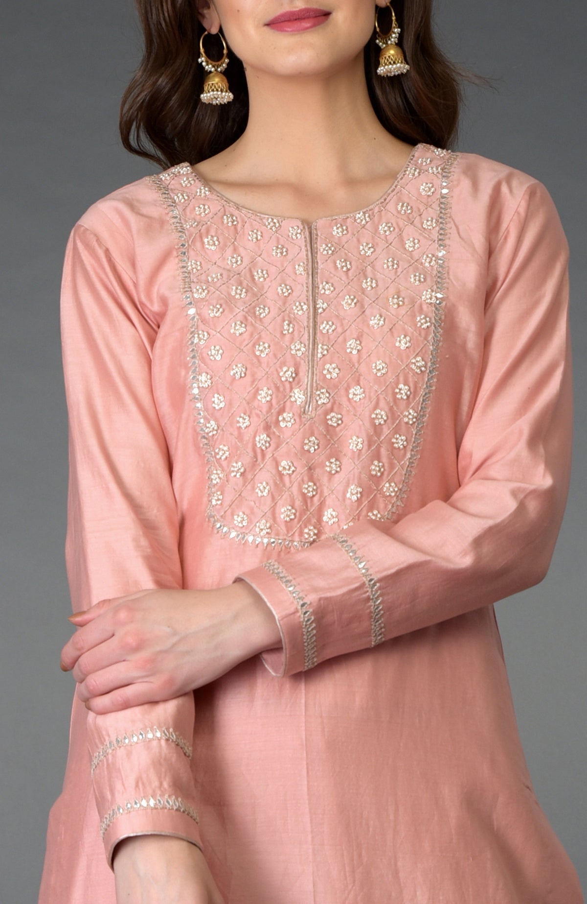 A woman models a pressed rose zardozi gota patti and pearl beads farshi suit.