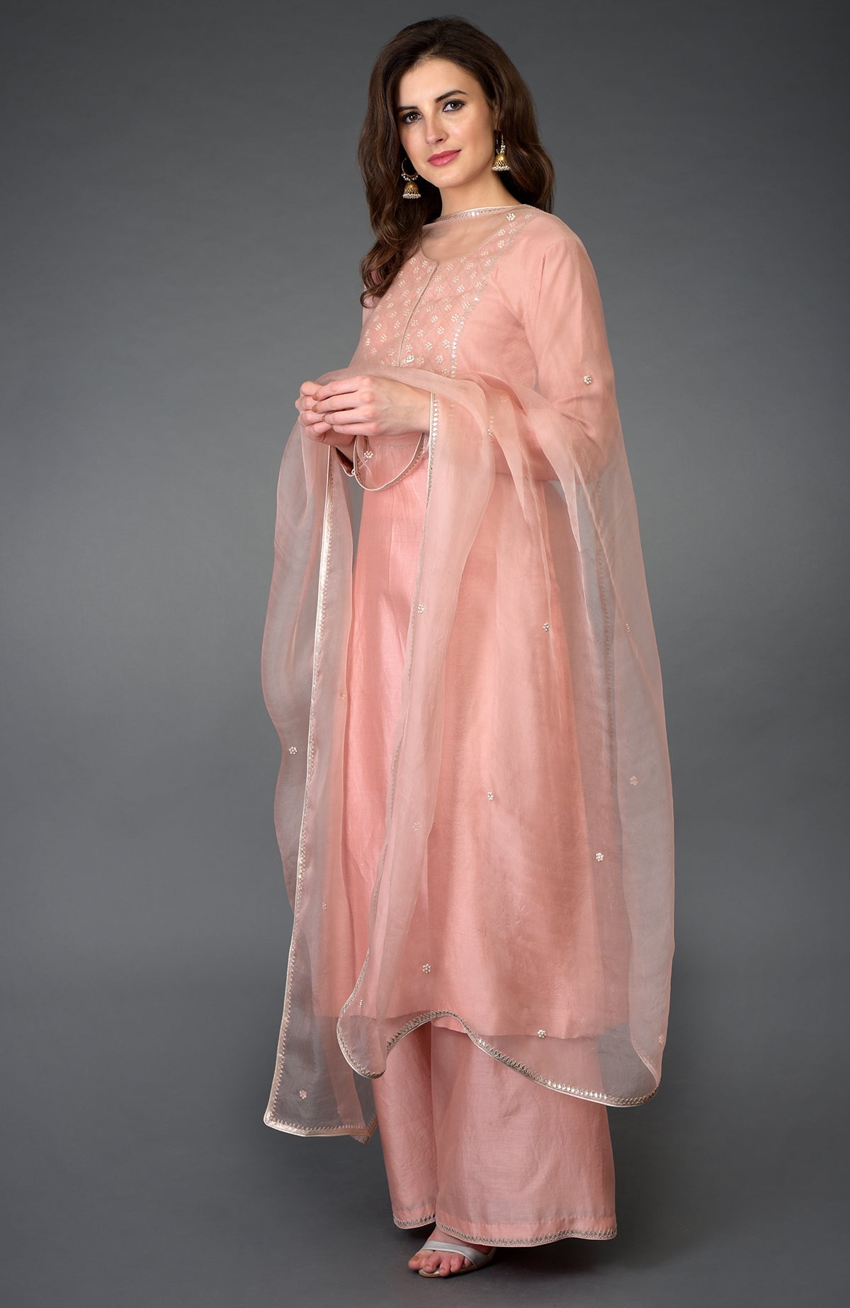 A woman models a pressed rose zardozi gota patti and pearl beads farshi suit.