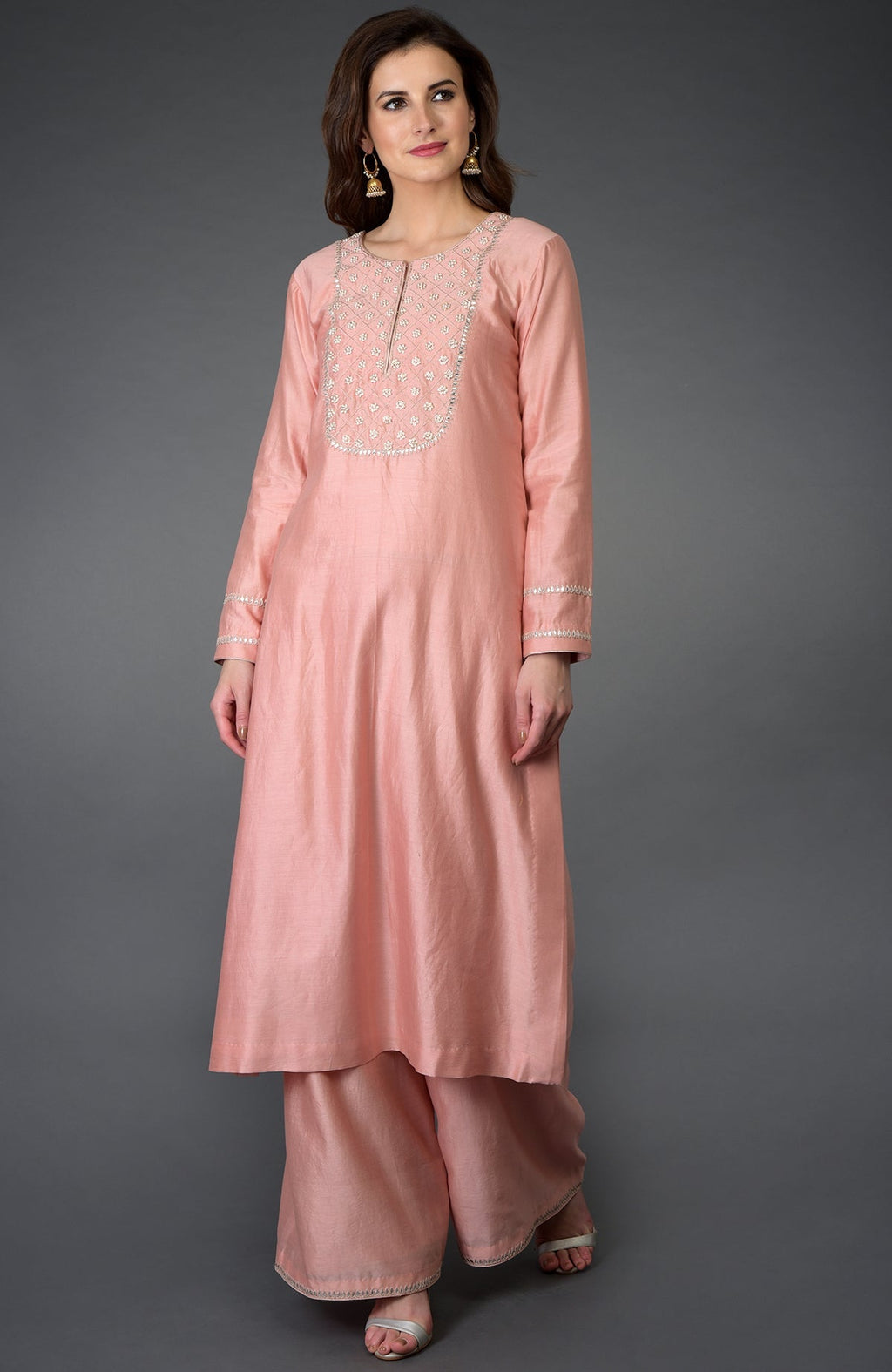 A woman models a pressed rose zardozi gota patti and pearl beads farshi suit.
