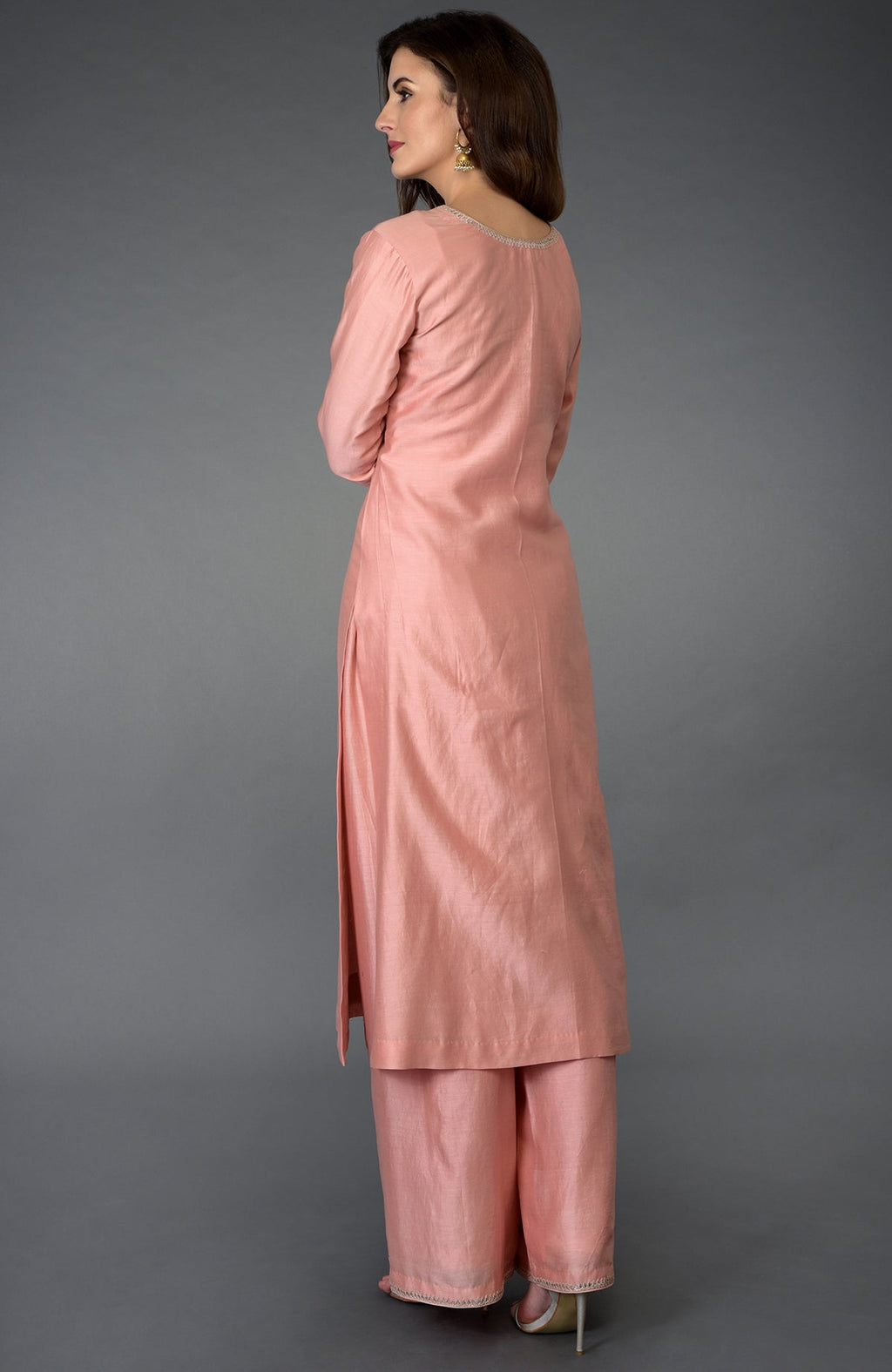 A woman models a pressed rose farshi suit with zardozi, gota patti, and pearl beads.