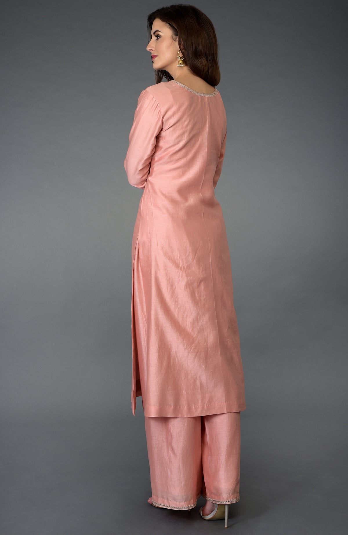 A woman models a pressed rose farshi suit with zardozi, gota patti, and pearl beads.