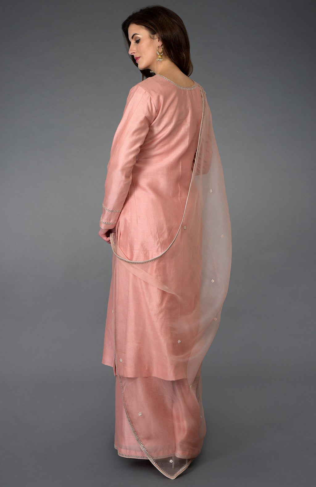 A woman models a pressed rose zardozi gota patti and pearl beads farshi suit.