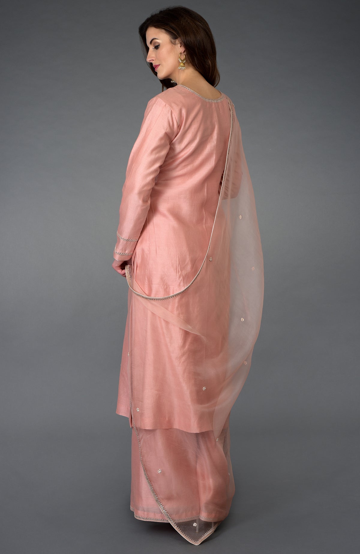 A woman models a pressed rose zardozi gota patti and pearl beads farshi suit.