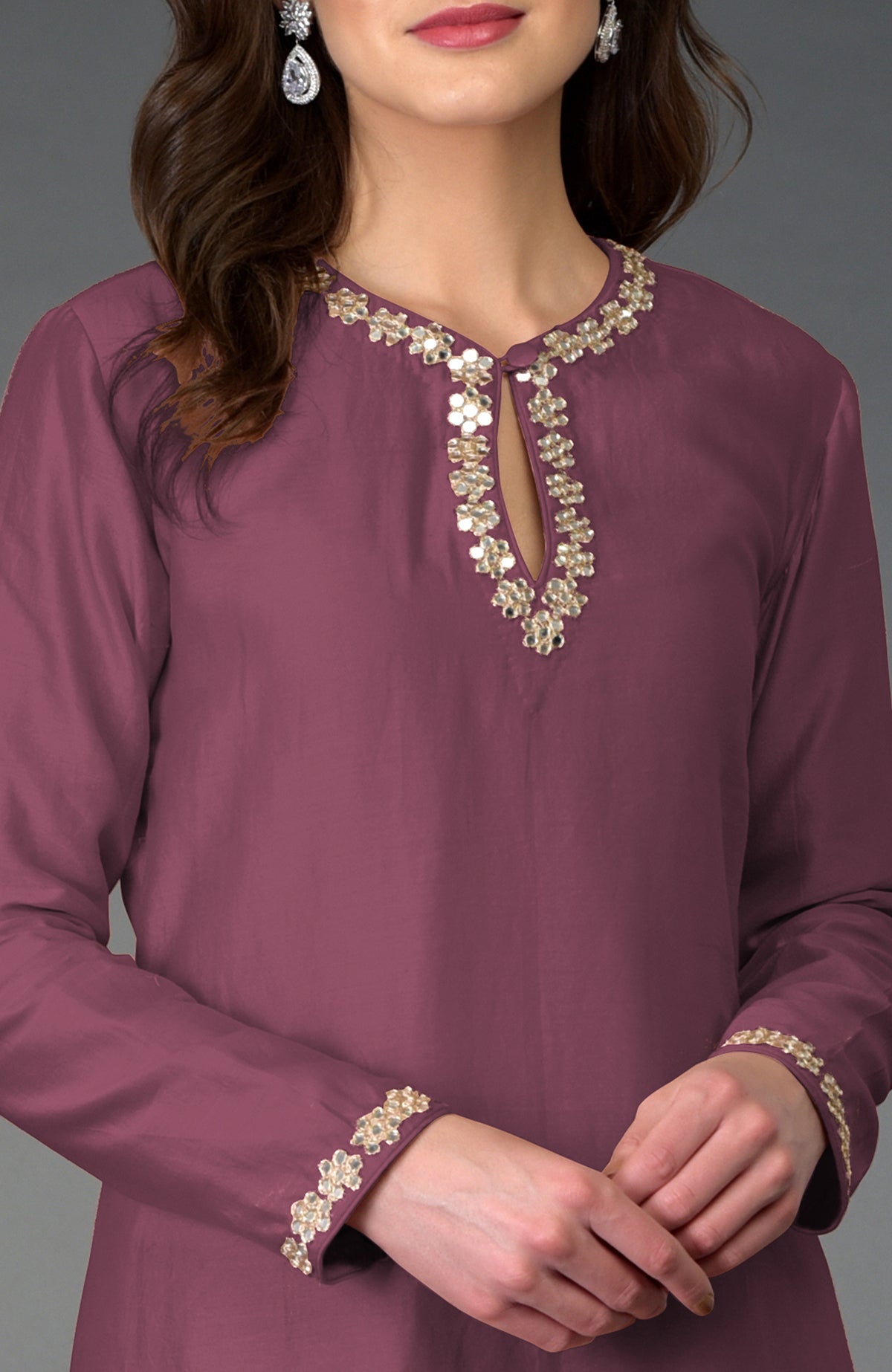 A woman wears a burgundy purple kurta with mirror and gota patti embroidery.