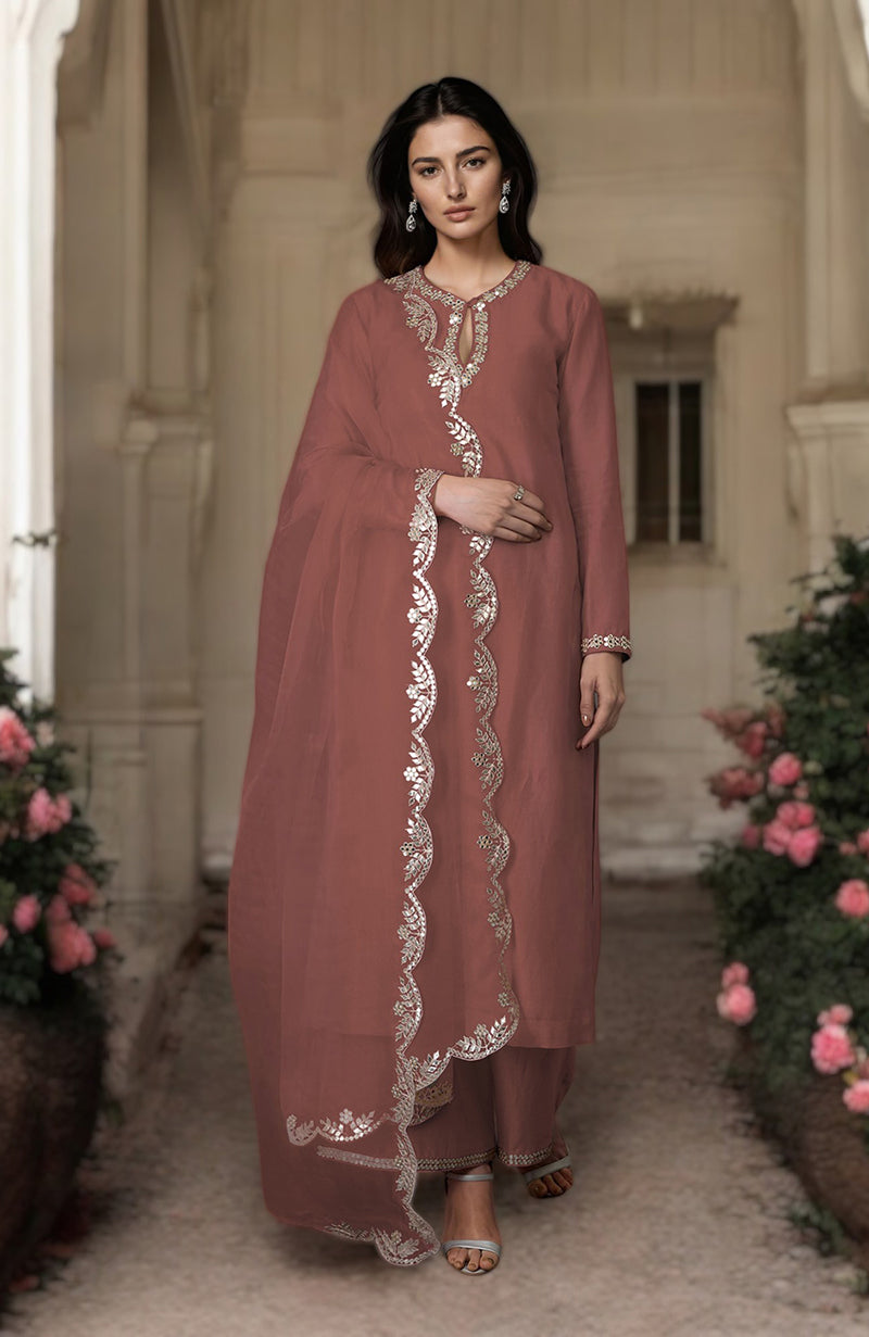 A woman models a pressed rose gota patti and mirror work farshi palazzo suit.