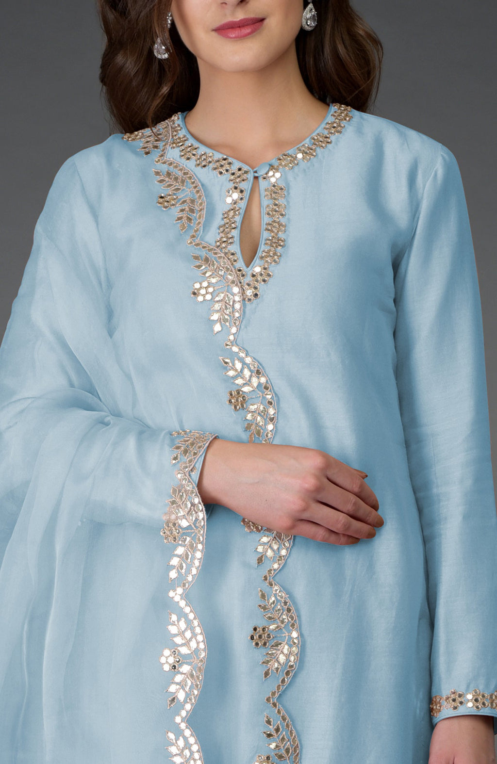 A woman models a light blue suit with gold and mirror embroidery.