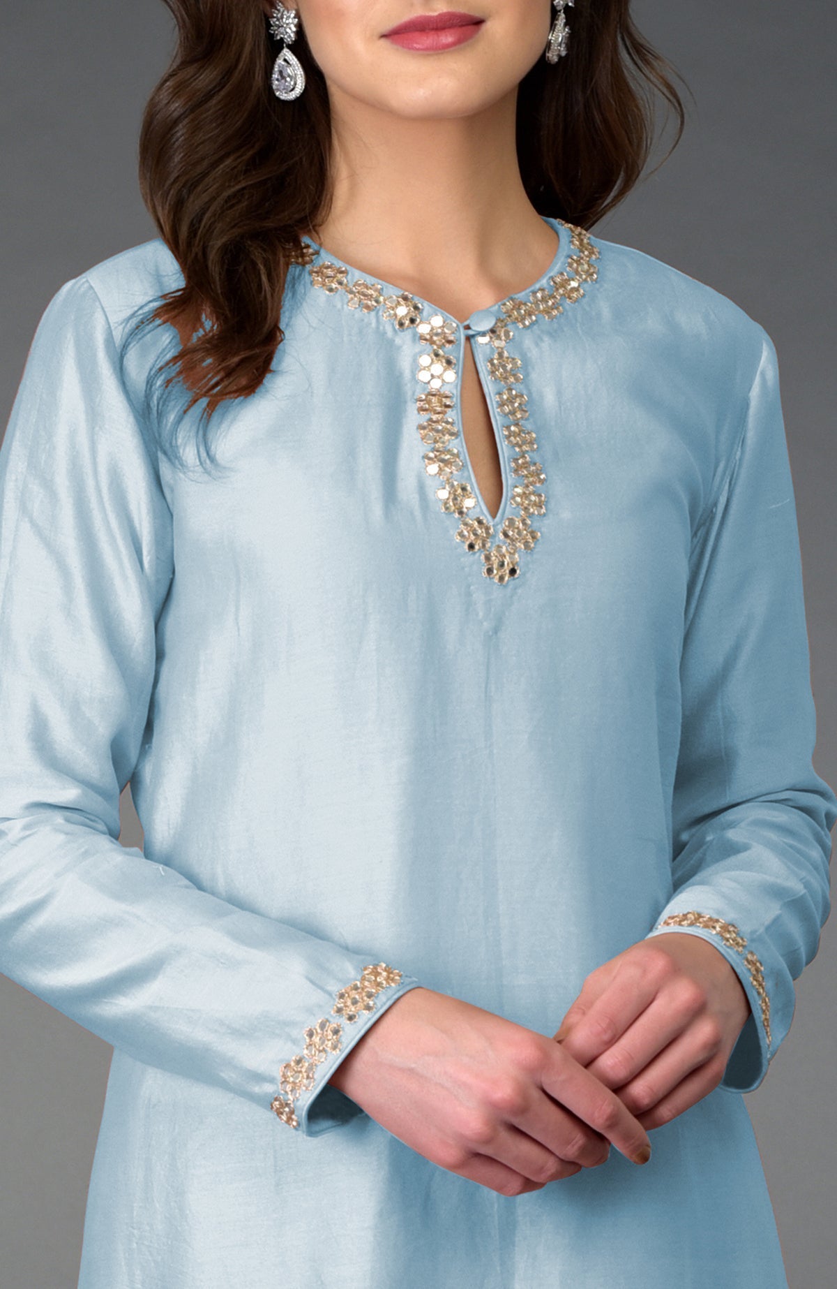 A woman models a light blue kurta with gold and mirror embroidery.
