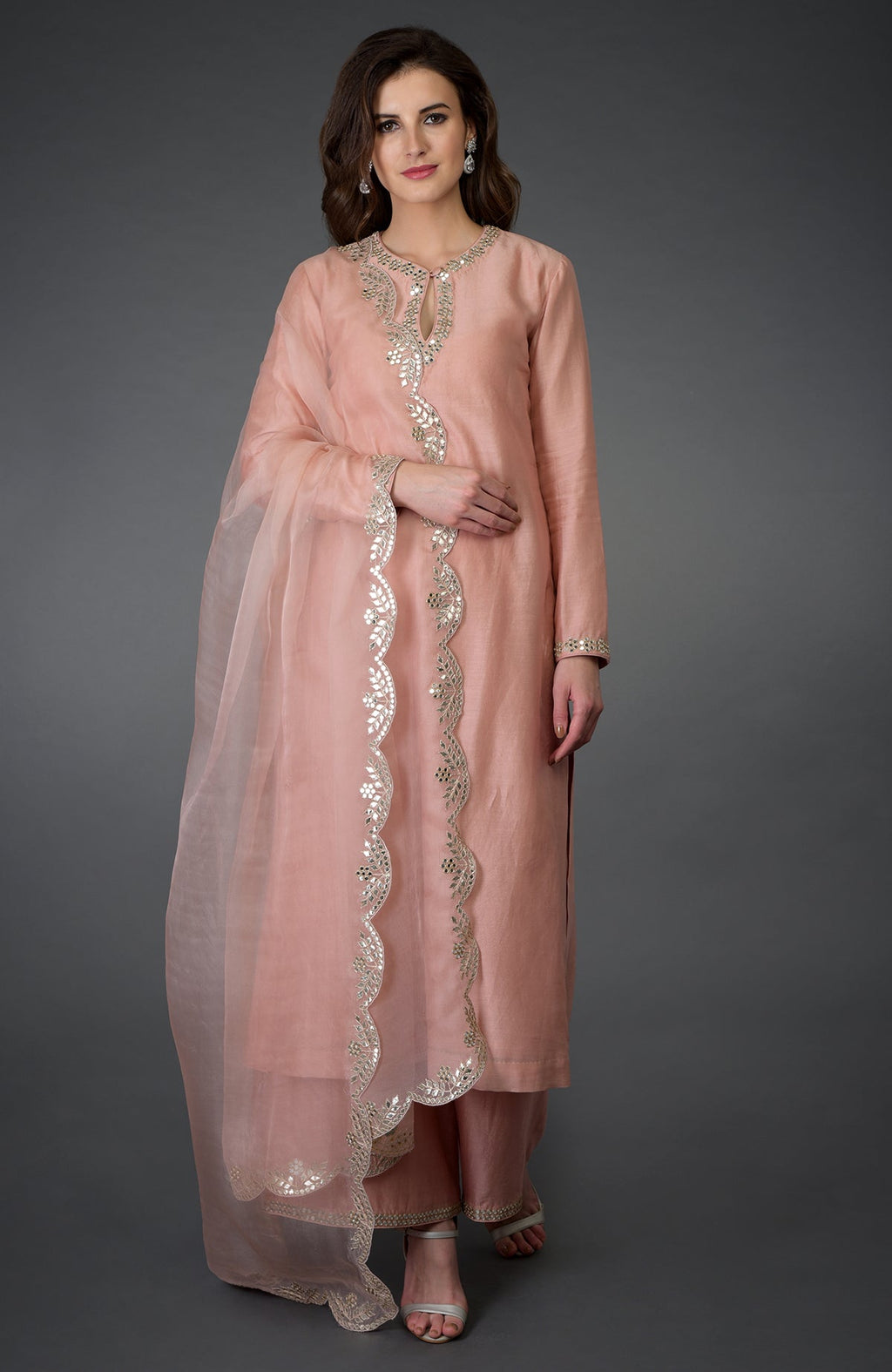 A woman models a pressed rose gota patti and mirror work farshi palazzo suit.
