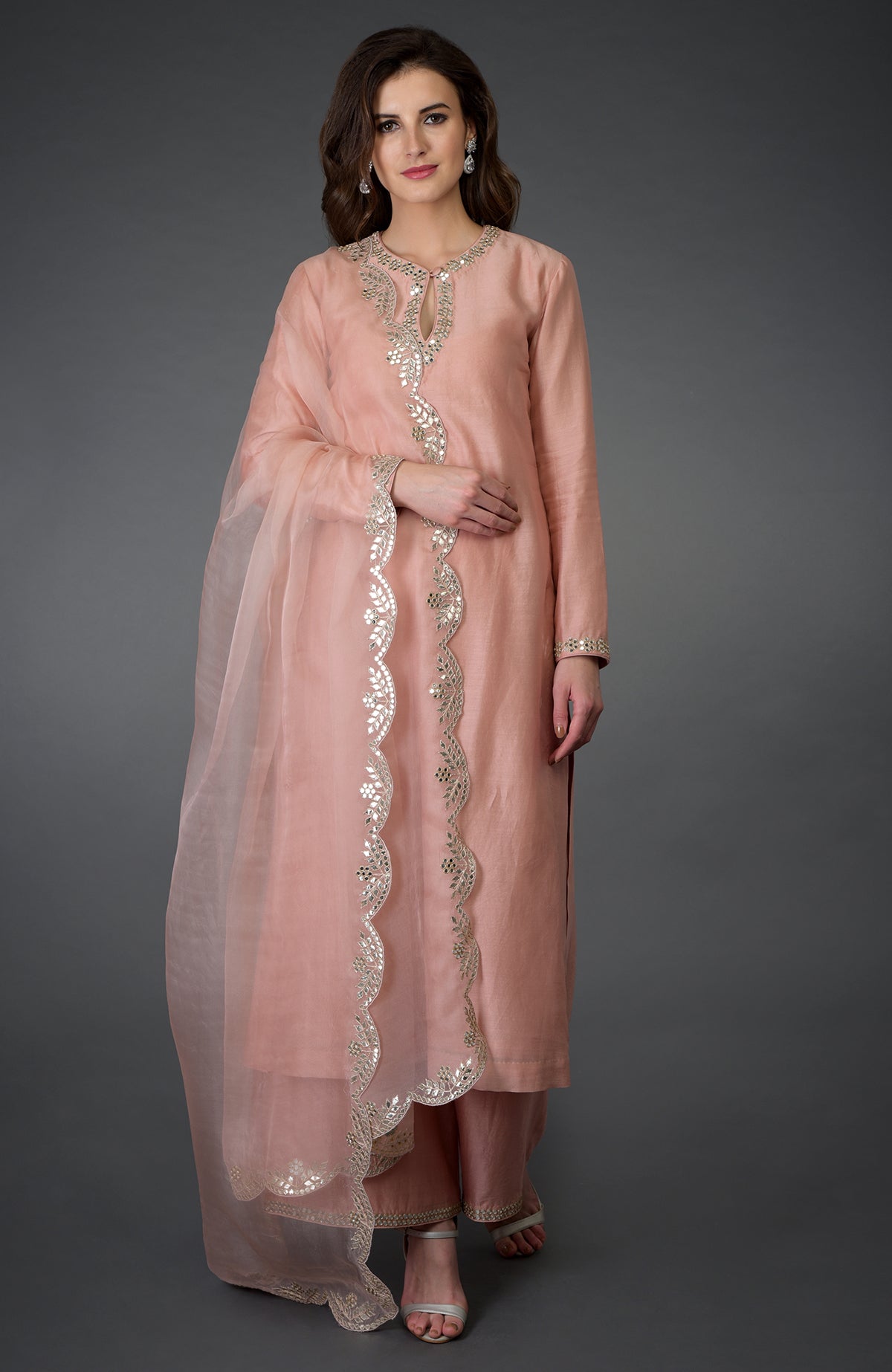 A woman models a pressed rose gota patti and mirror work farshi palazzo suit.