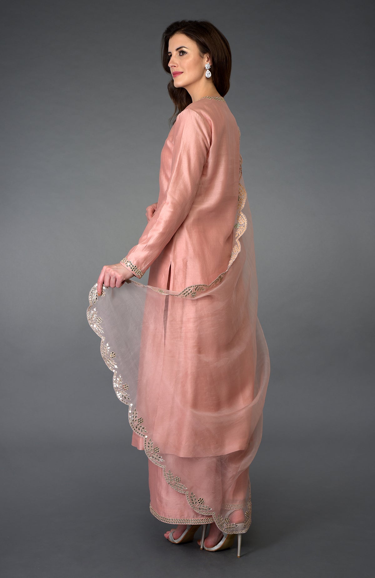 A woman models a pressed rose gota patti and mirror work farshi palazzo suit.