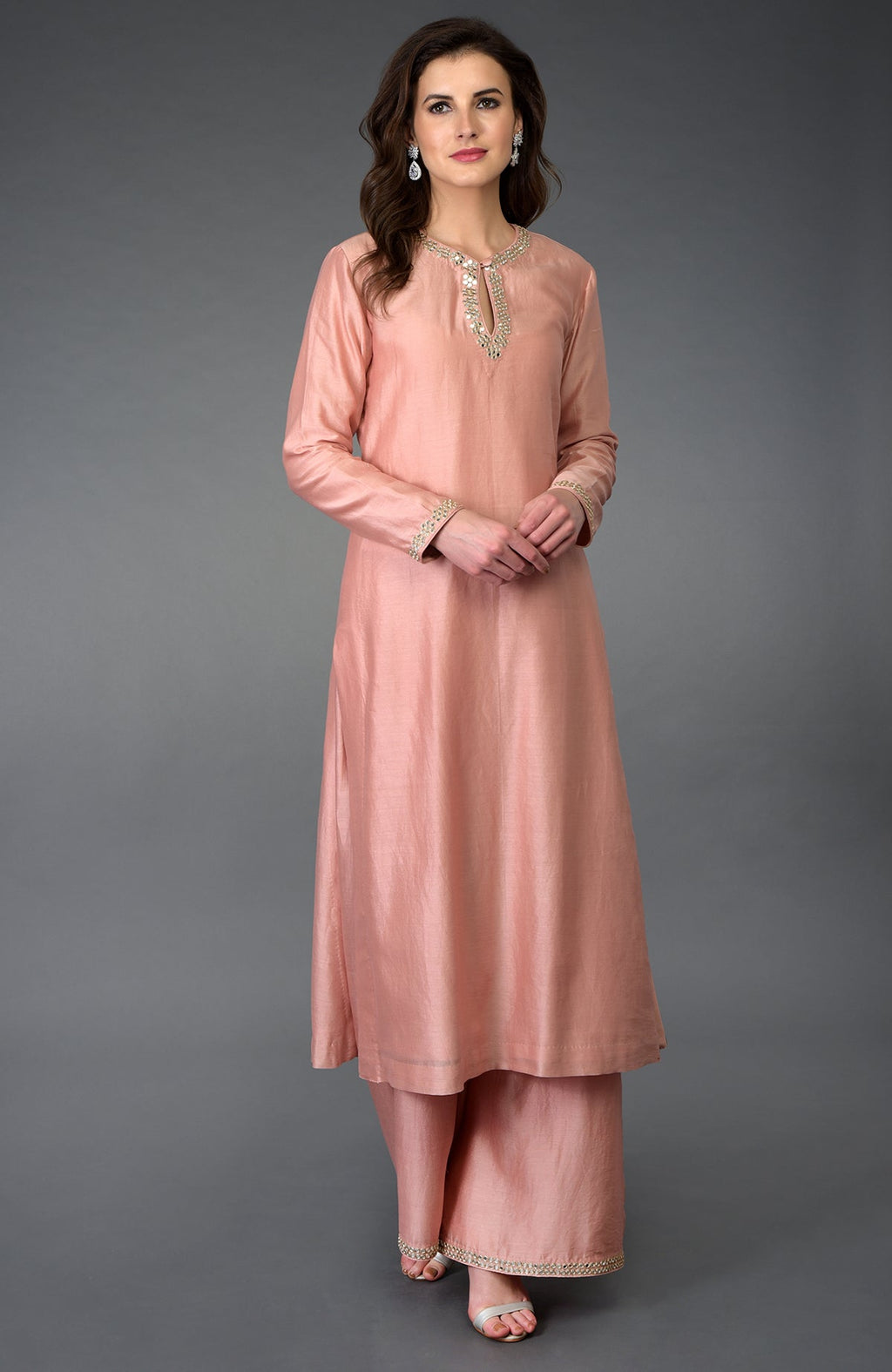 A woman models a pressed rose farshi palazzo suit with mirror and gota patti work.