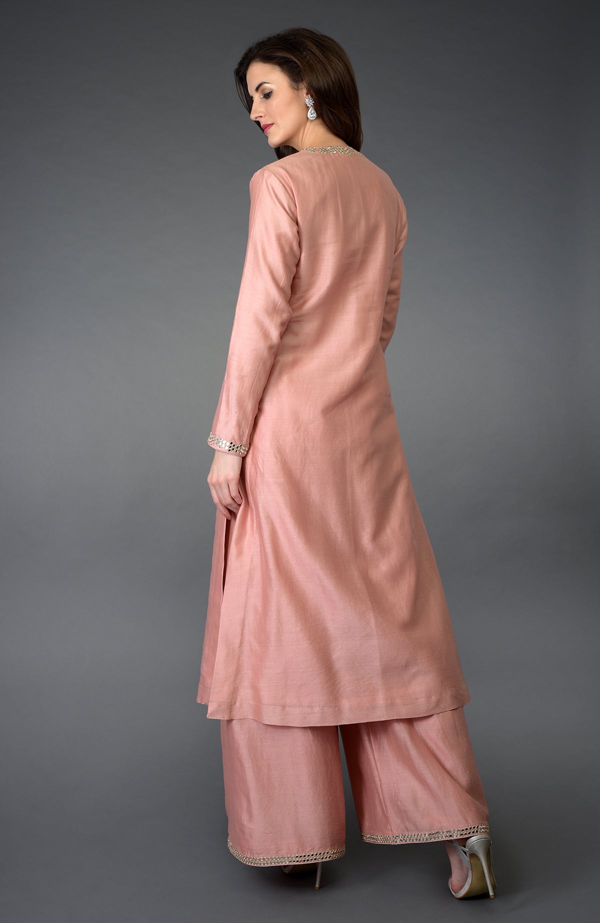 A woman models a pressed rose gota patti and mirror work farshi palazzo suit.