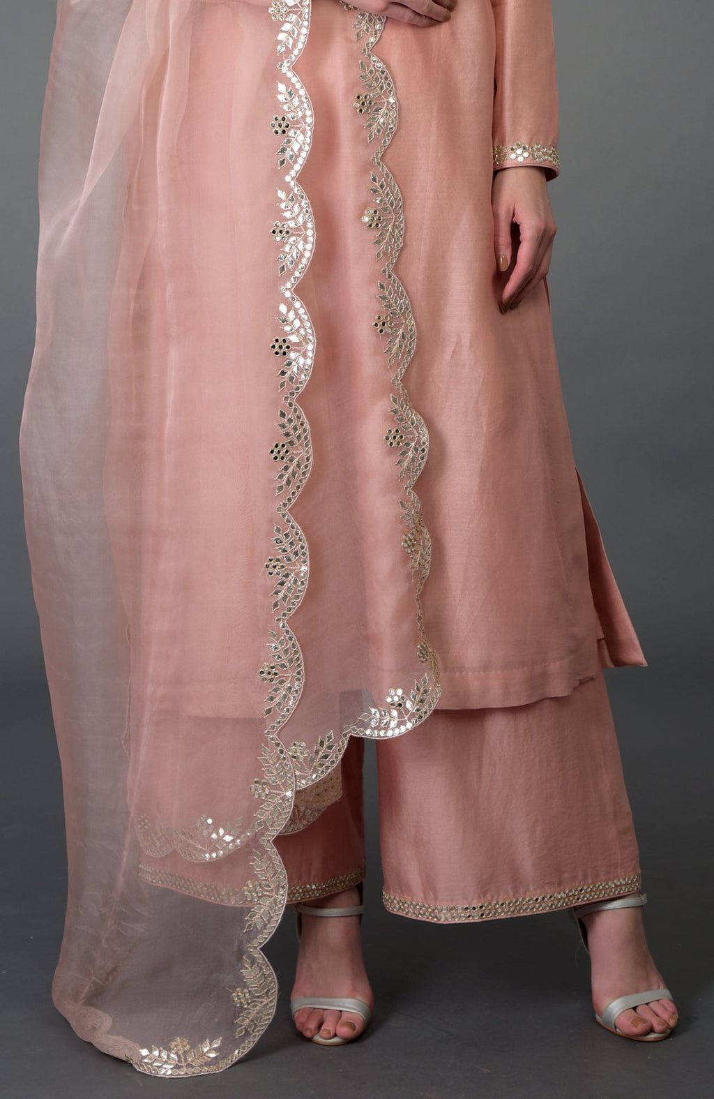 A woman models a pressed rose gota patti and mirror work farshi palazzo suit.