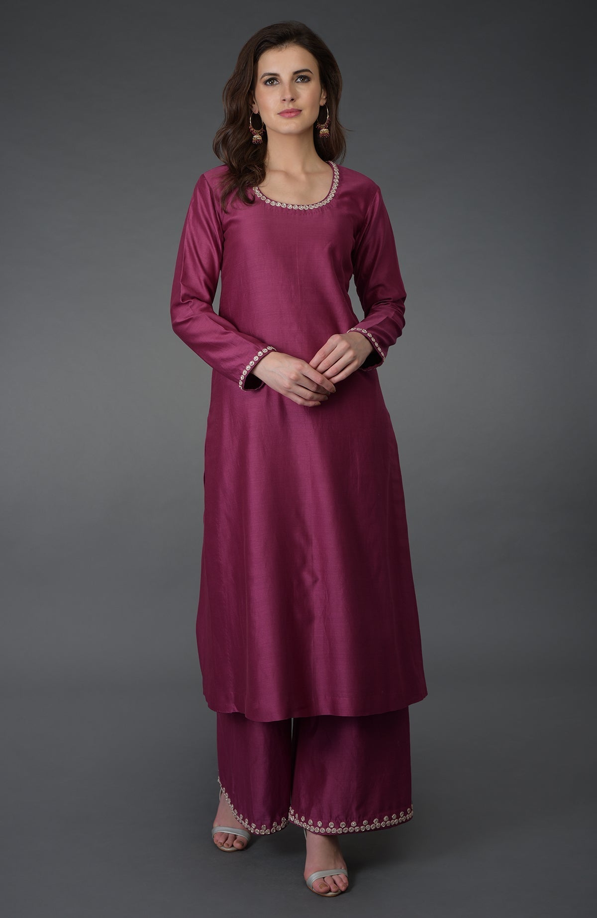 A woman models a burgundy zardozi gota patti and crystal work farshi suit.