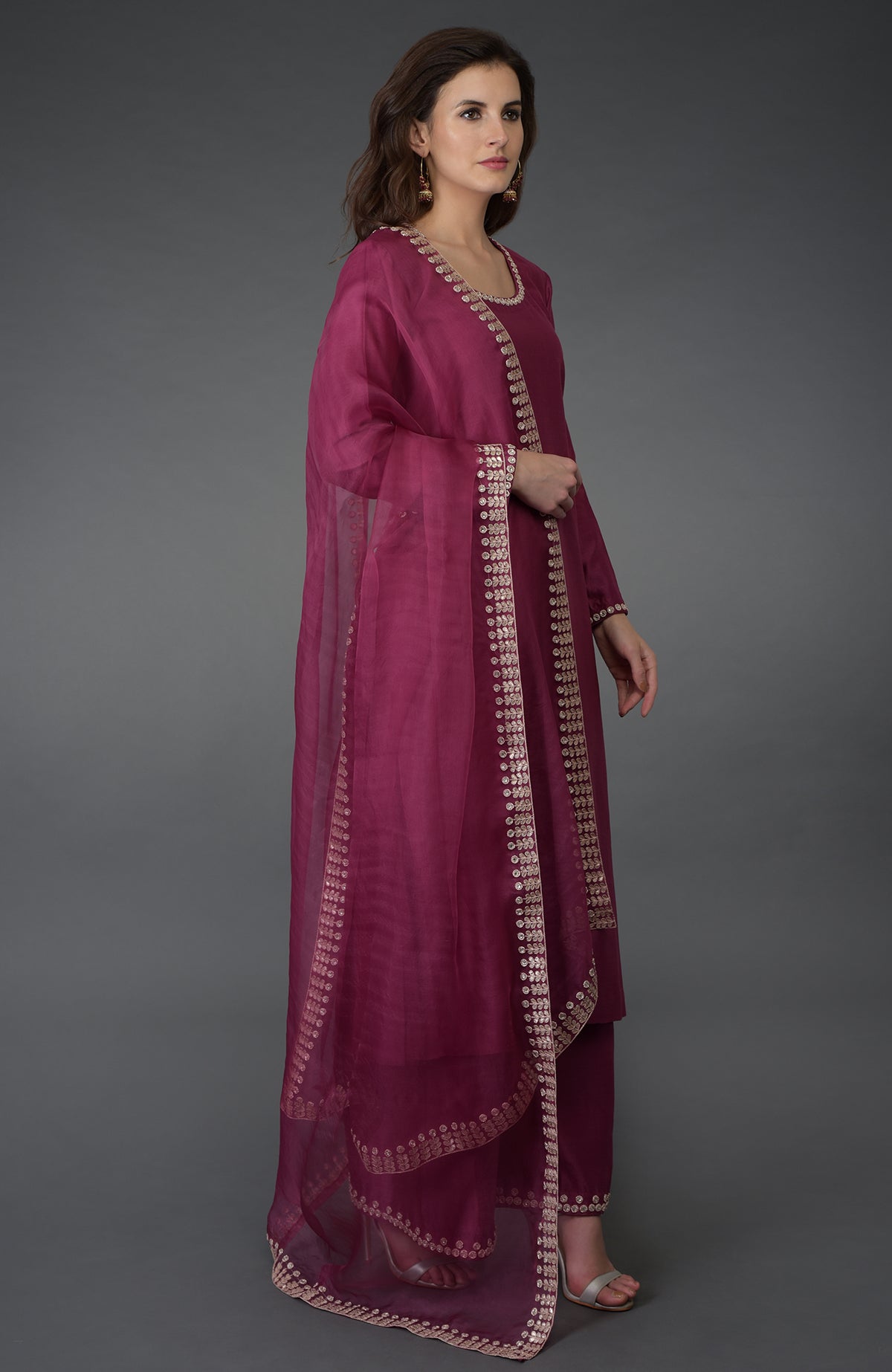 A woman models a burgundy zardozi gota patti and crystal work farshi suit.