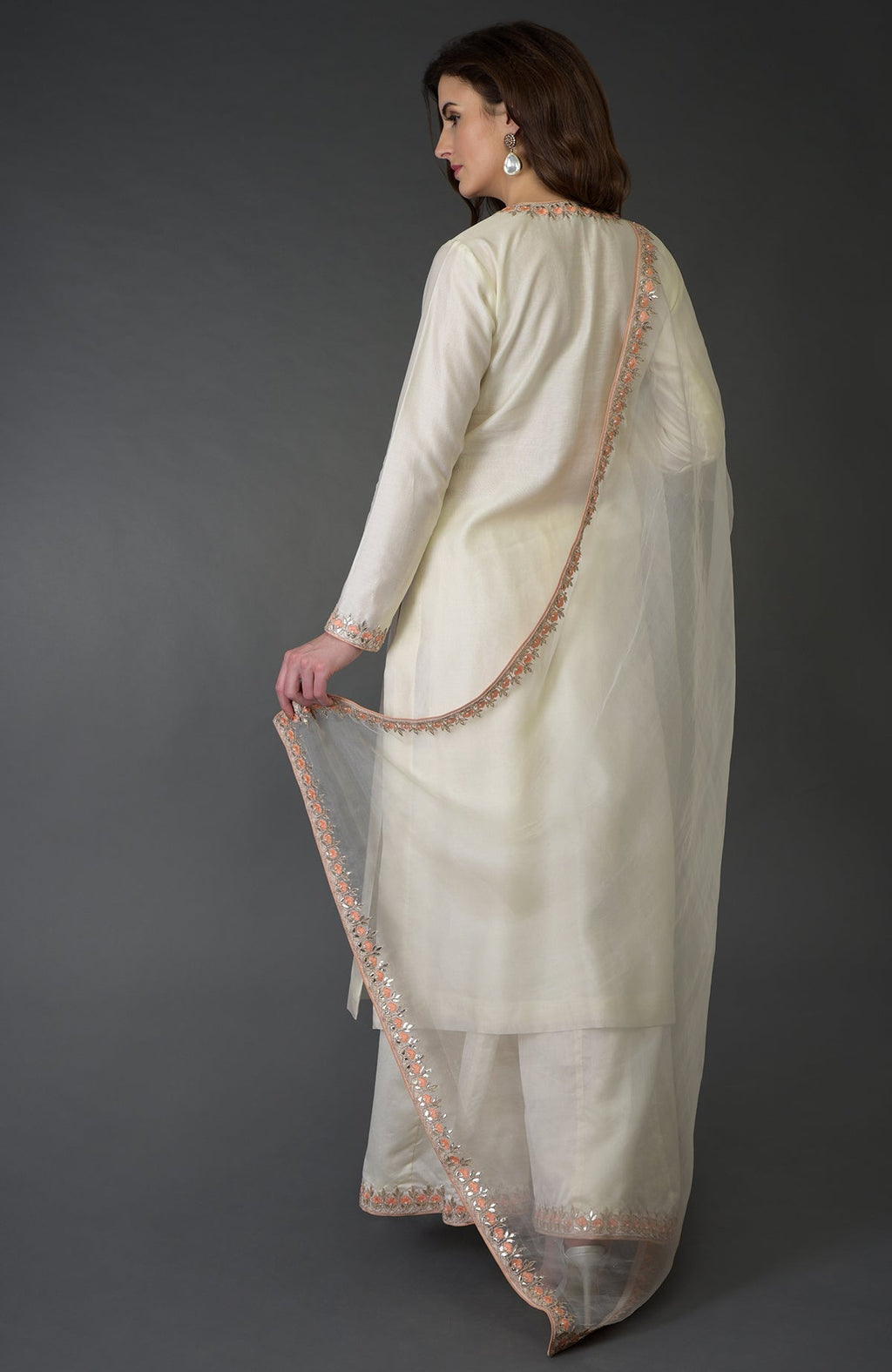 A woman models an ivory Resham Gota Patti and Pearl Beads Farshi Palazzo Suit.