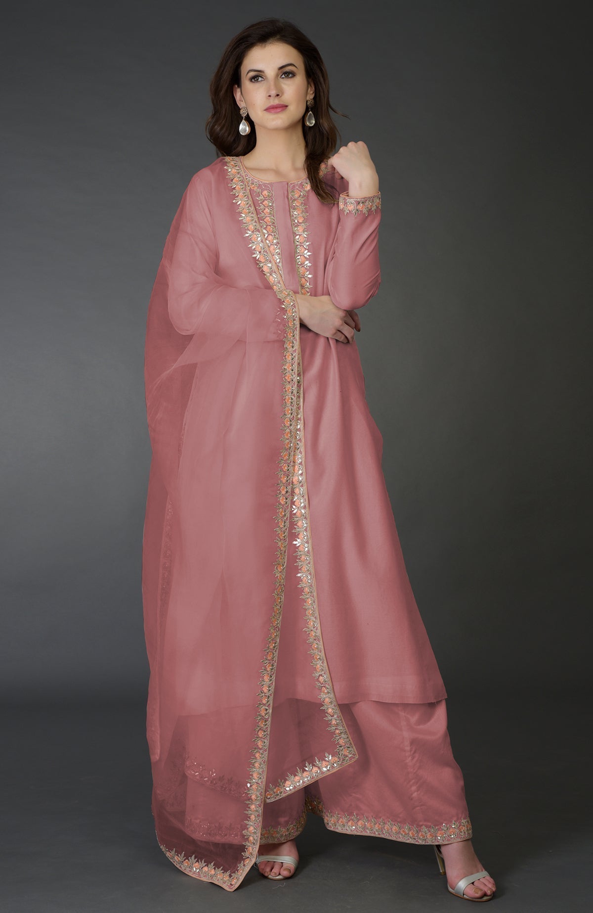 A woman models an embroidered pink palazzo suit with a matching dupatta.