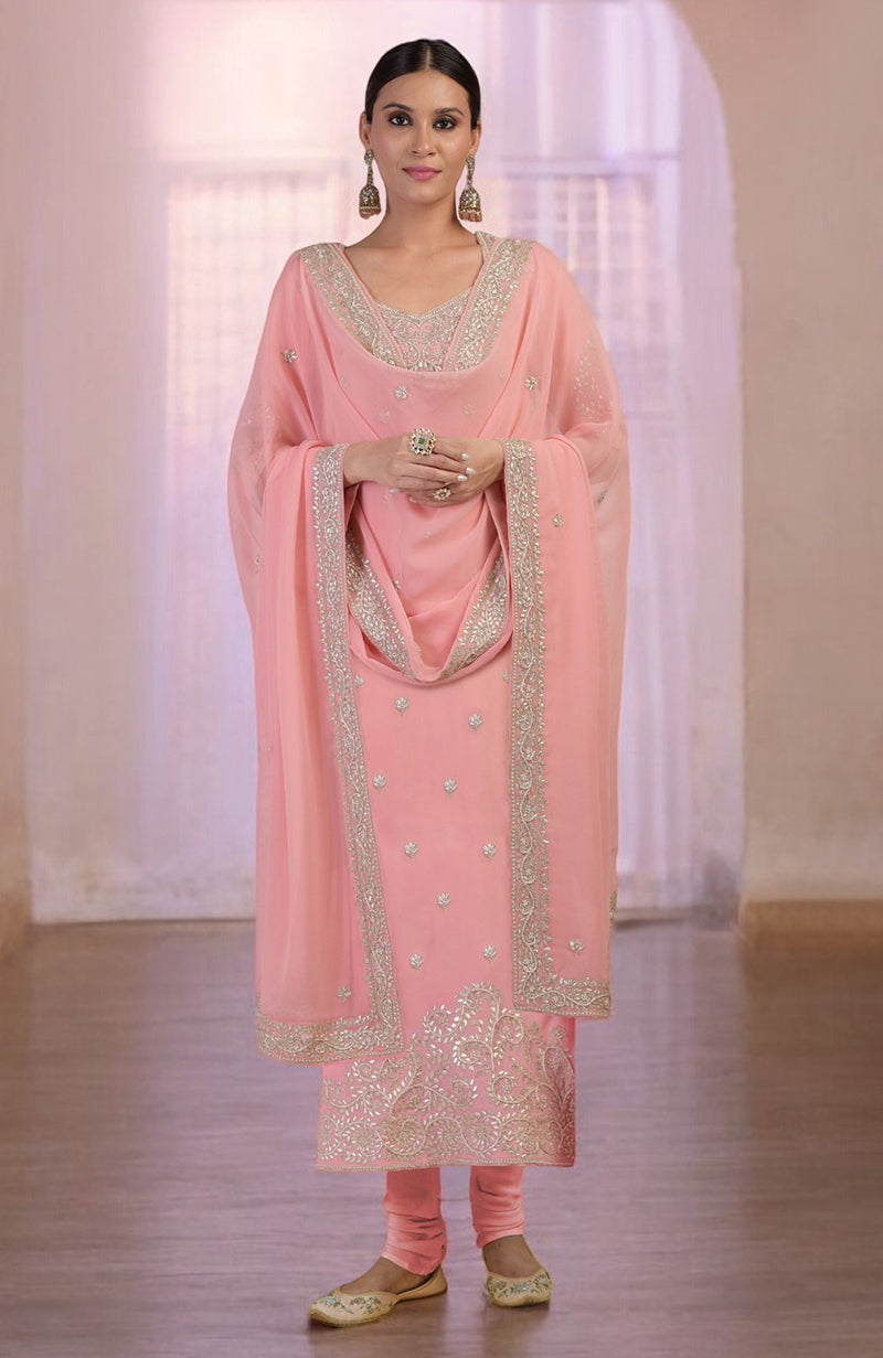 A woman models a pink kurta set with silver embroidery and matching shoes.