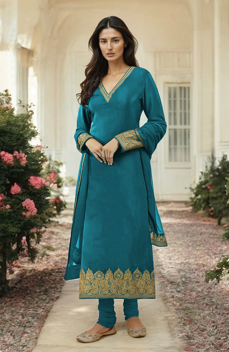 A woman models a teal kurta set with gold embroidery and matching pants.