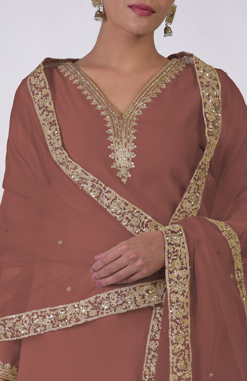 A woman wears a chutney-colored kurta set with gold marori and zardozi embroidery.