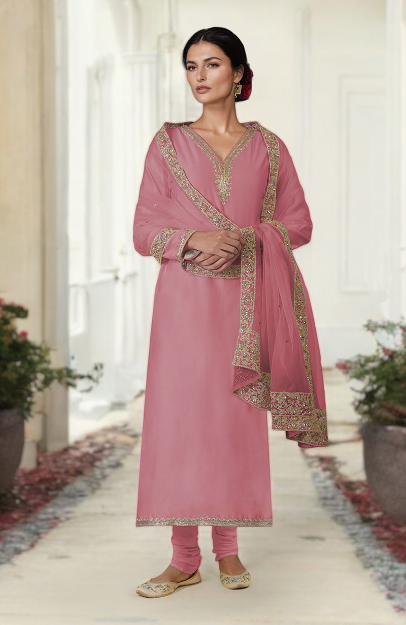 A woman models a pink kurta set with gold embroidery and a matching dupatta.