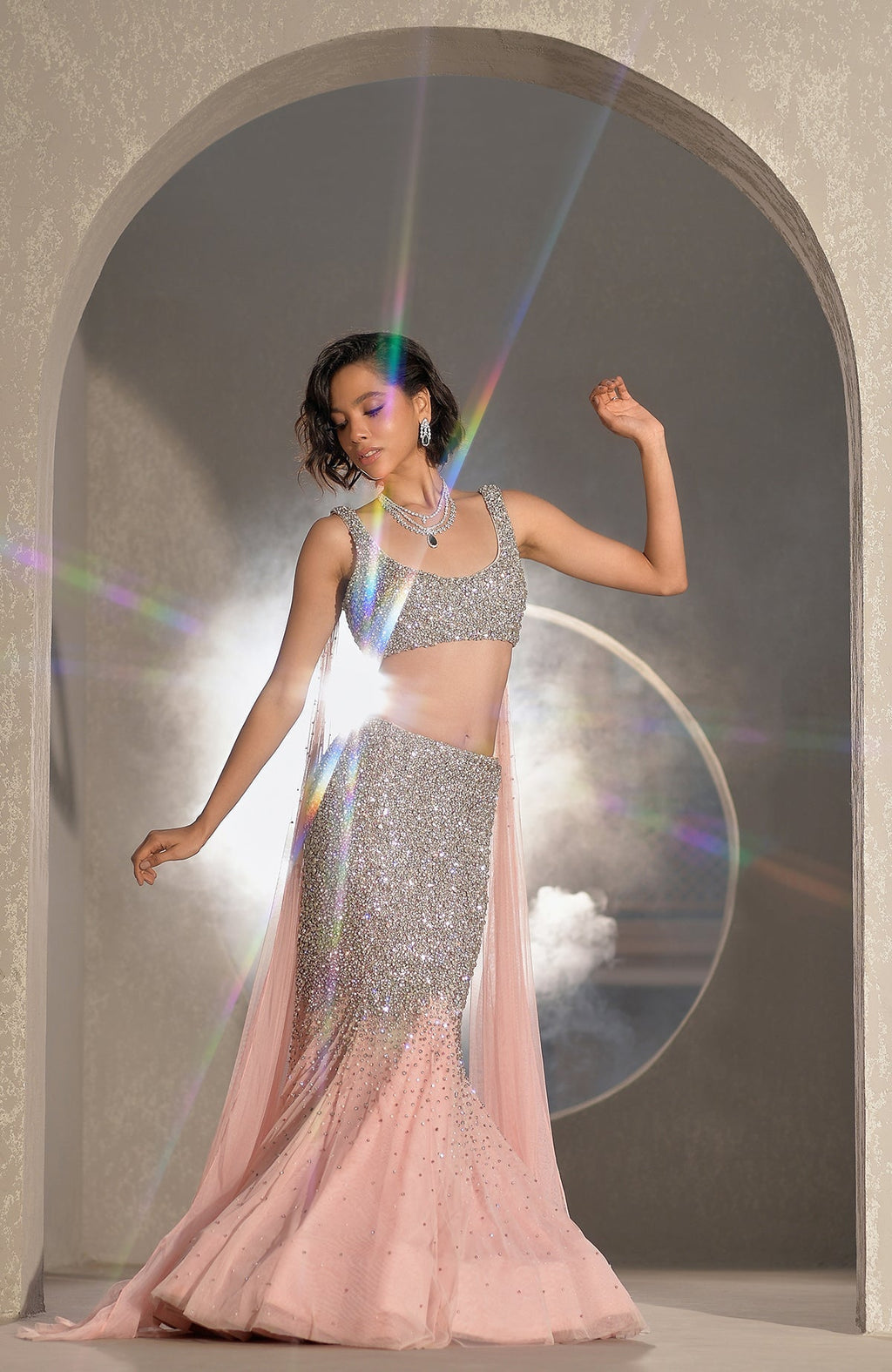 Pink mermaid lehenga with hand-embroidered crystals and pearls, paired with a sheer cape.
