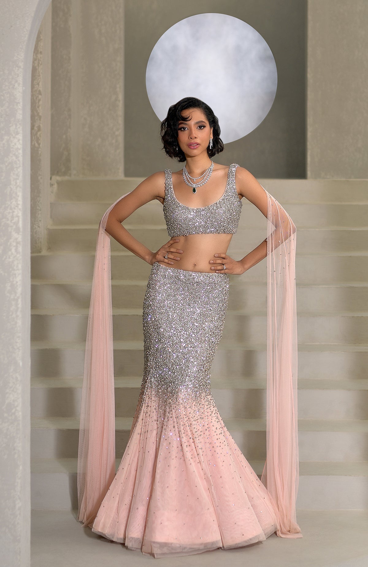 Pink mermaid lehenga with hand-embroidered crystals and pearls, paired with a sheer cape.
