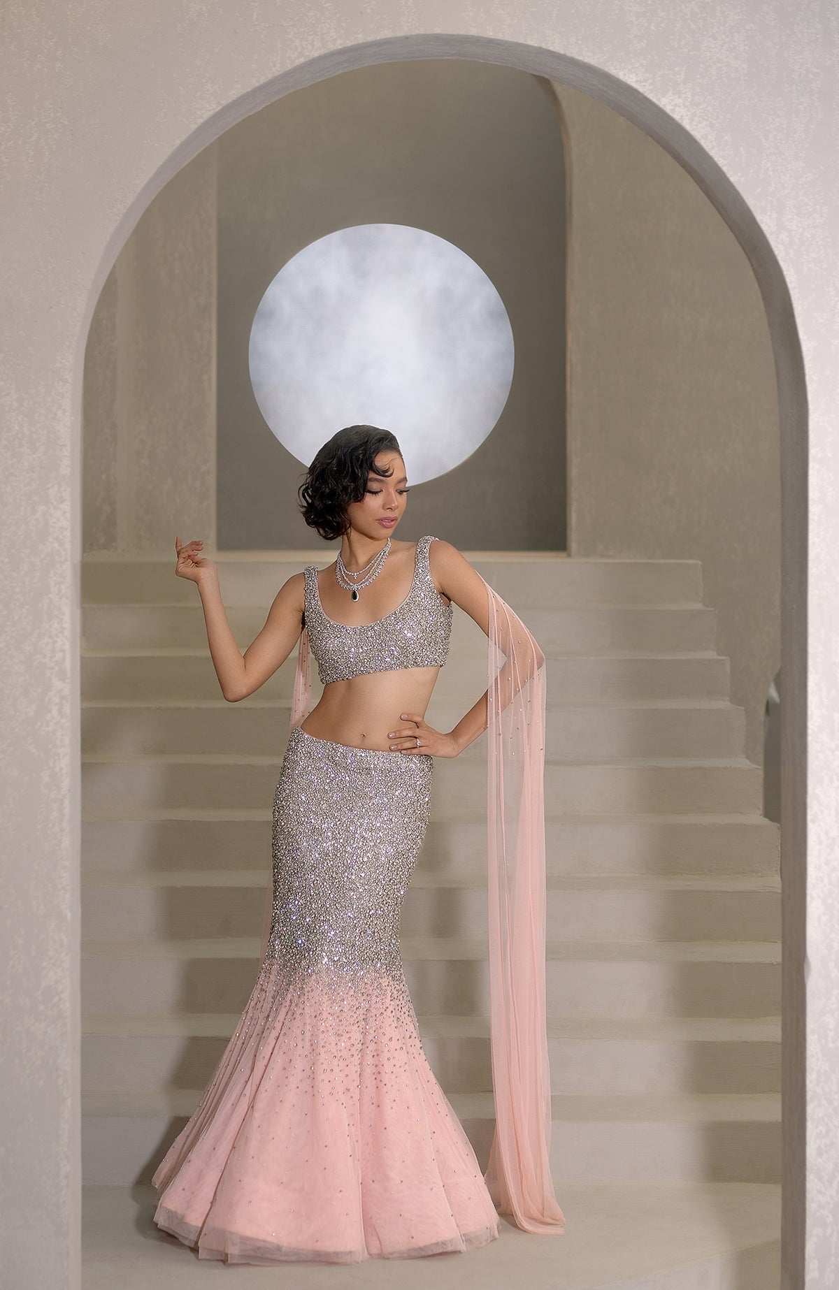 Pink mermaid lehenga with hand-embroidered crystals and pearls, paired with a sheer cape.