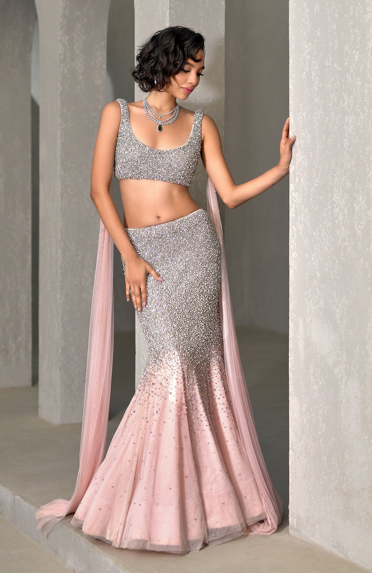 Pink mermaid lehenga with hand-embroidered crystals and pearls, paired with a sheer cape.