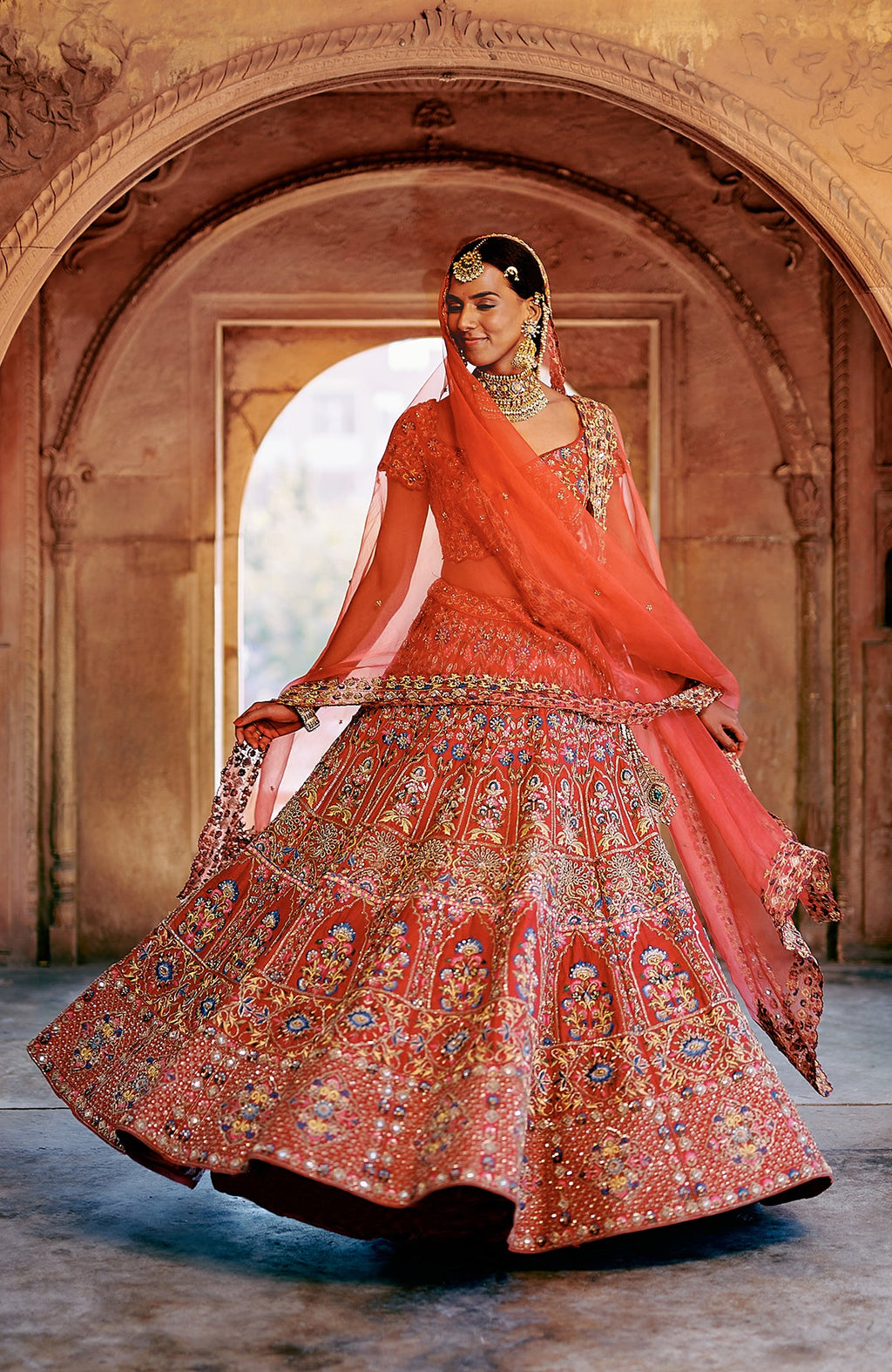 Red multicolour lehenga set with intricate embroidery, peacock tassels, and sheer dupatta.