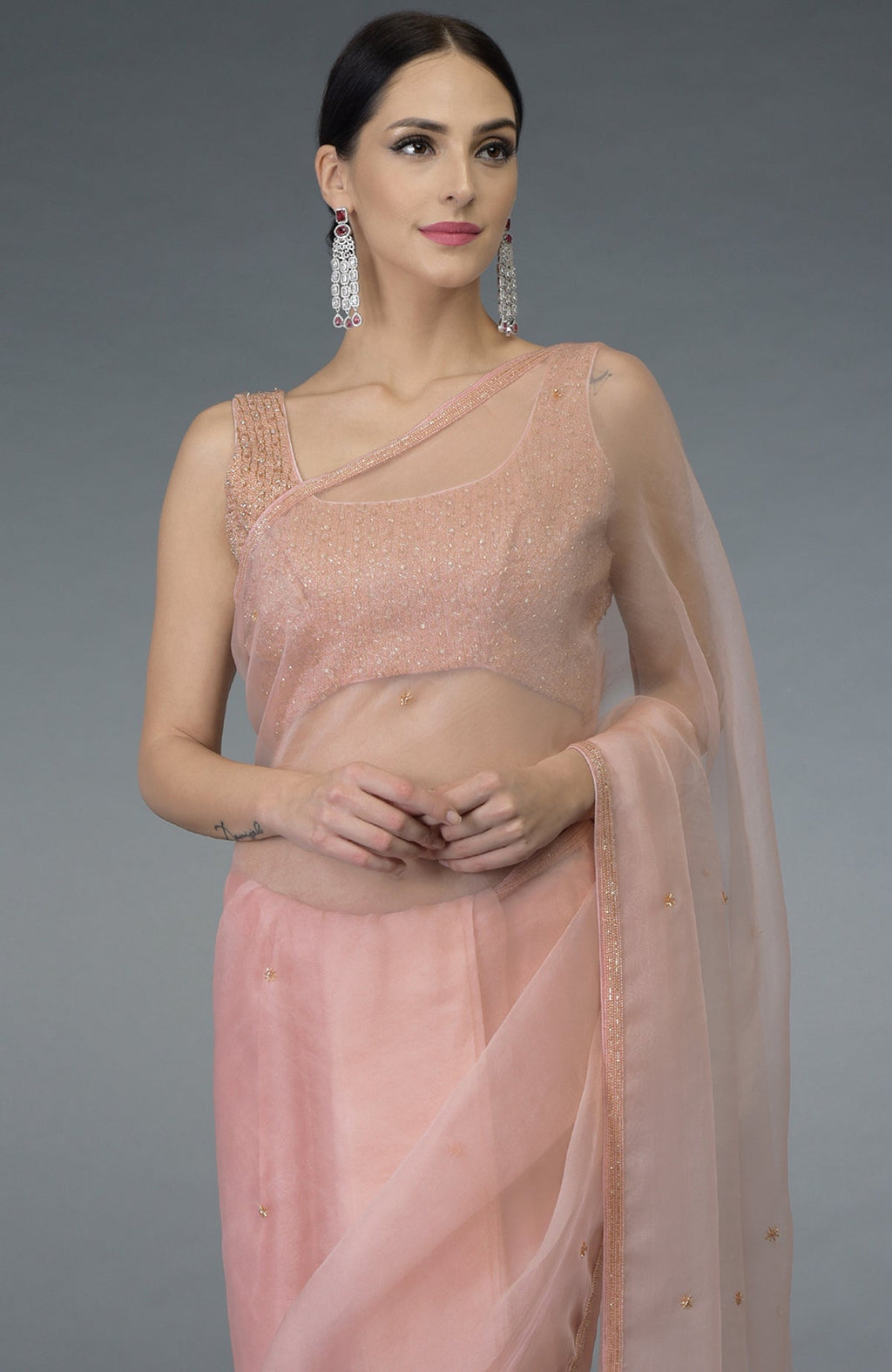 Pastel peach organza silk saree with a hand-embroidered blouse and statement earrings.