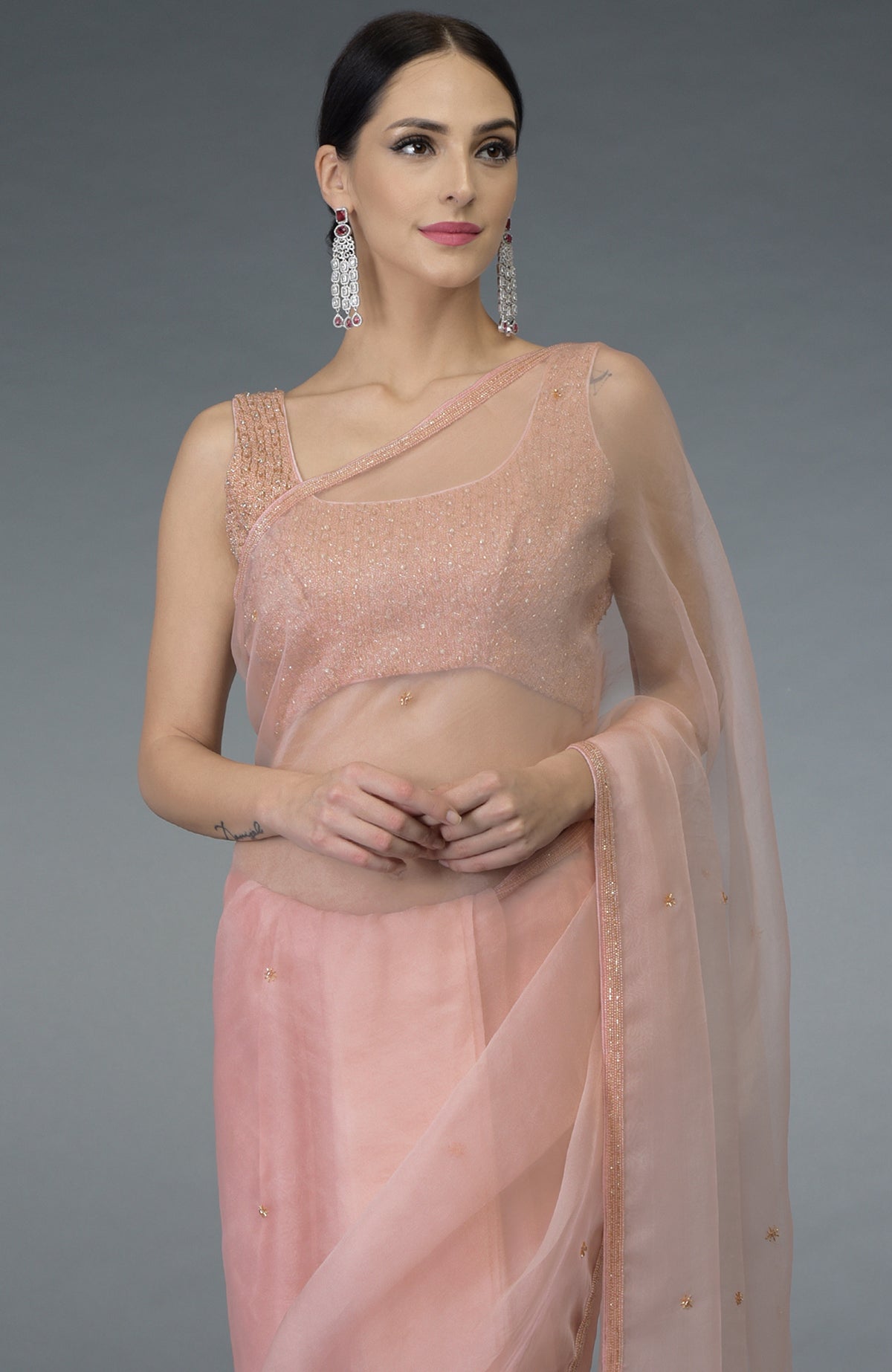 Pastel peach organza silk saree with a hand-embroidered blouse and statement earrings.